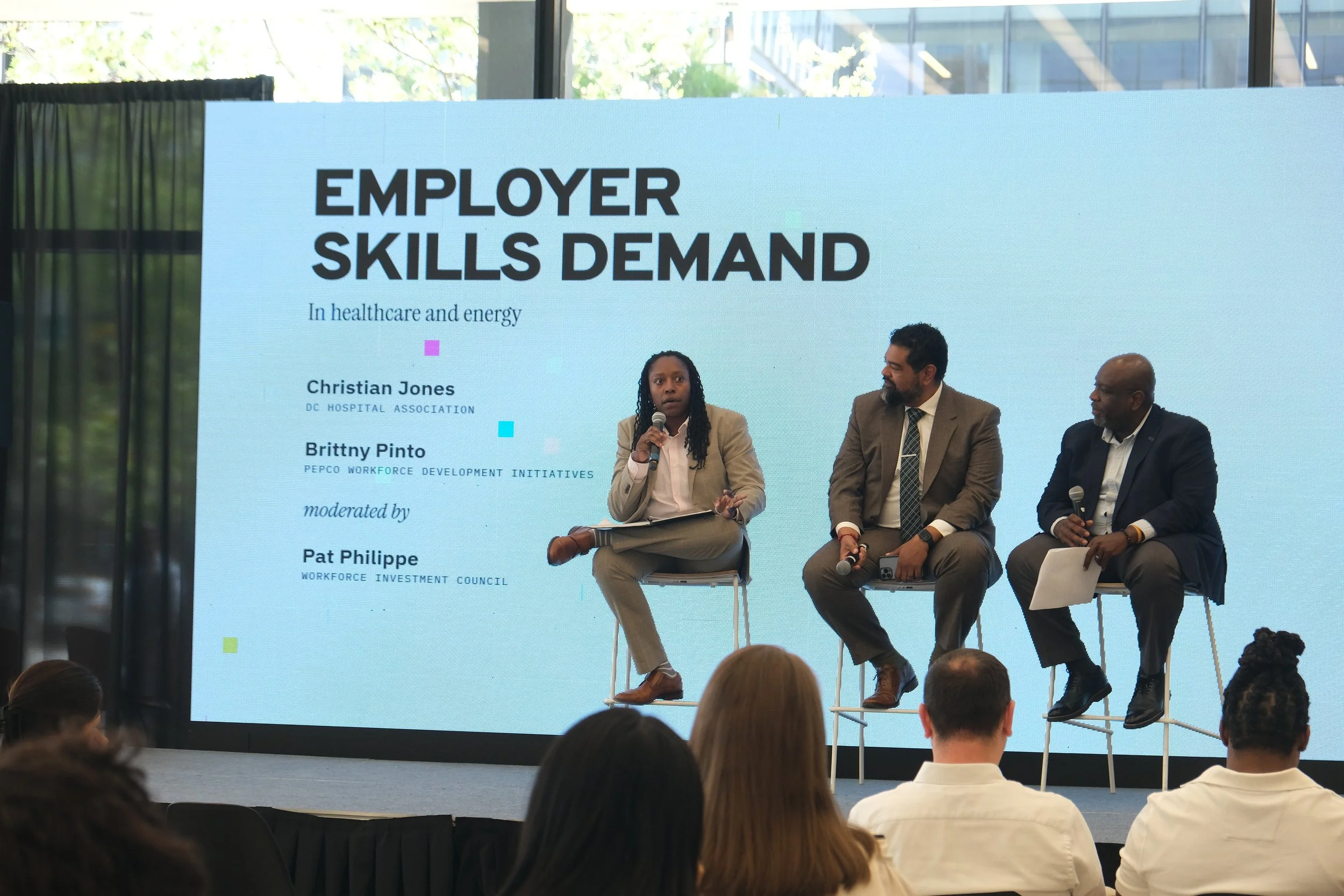 Brittny Pinto with microphone in hand talking about employer skills in demand while Christian Jones and Pat Philippe sit to the right to her on stage.