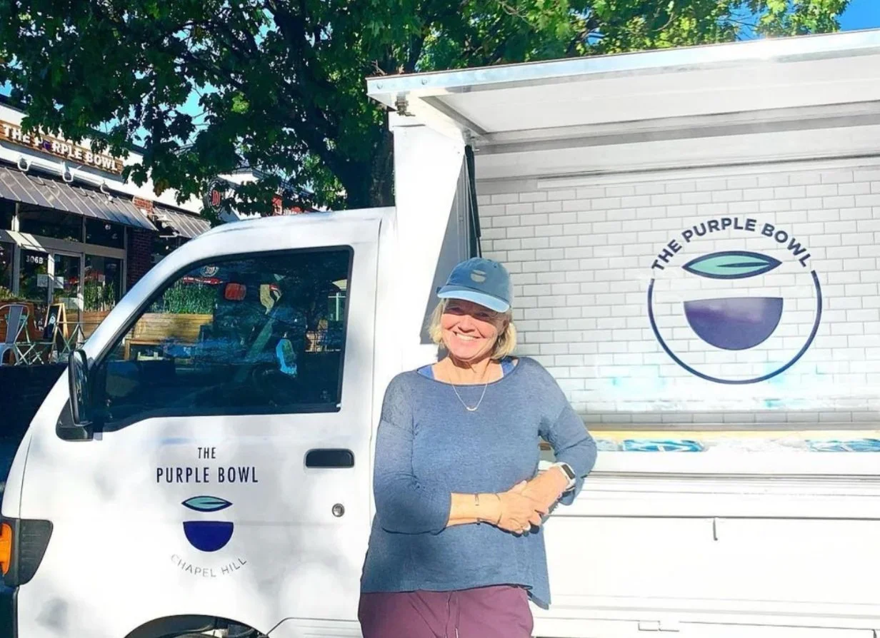 Paula, the owner of The Purple Bowl, standing in front of The Purple Bowl catering truck