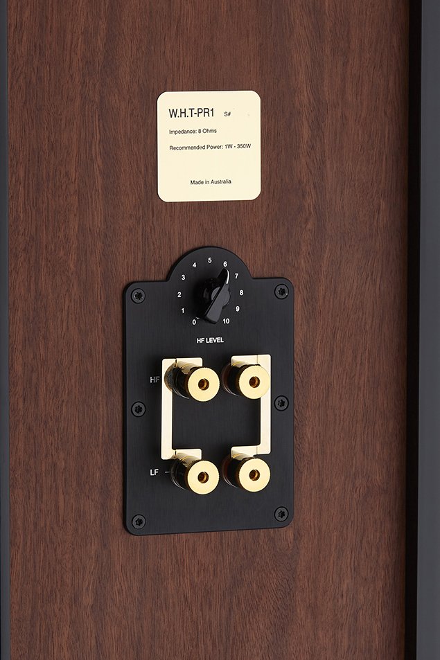 Nahaufnahme eines Lautsprecheranschlusses mit vier Anschlüssen, zwei für Hochfrequenz (HF) und zwei für Niederfrequenz (LF), an einer Holzoberfläche.