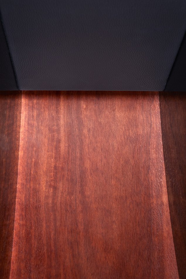 Ein dunkler Möbelstück oder eine Wand neben einem Holzboden.