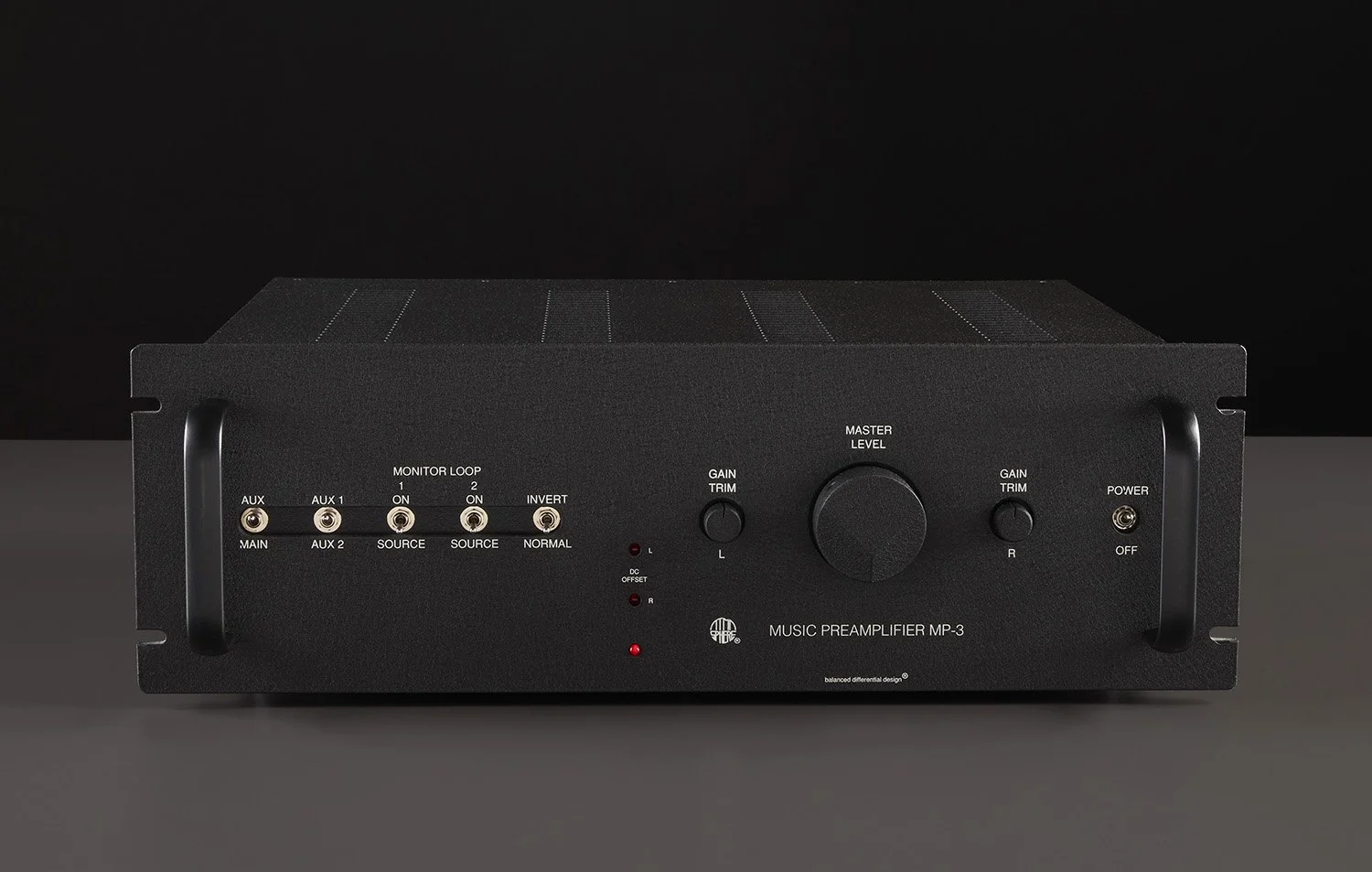 Ein schwarzer Musikvorverstärker mit mehreren Anschlüssen, Drehknöpfen und LED-Lichtern auf einer grauen Oberfläche vor einem schwarzen Hintergrund.