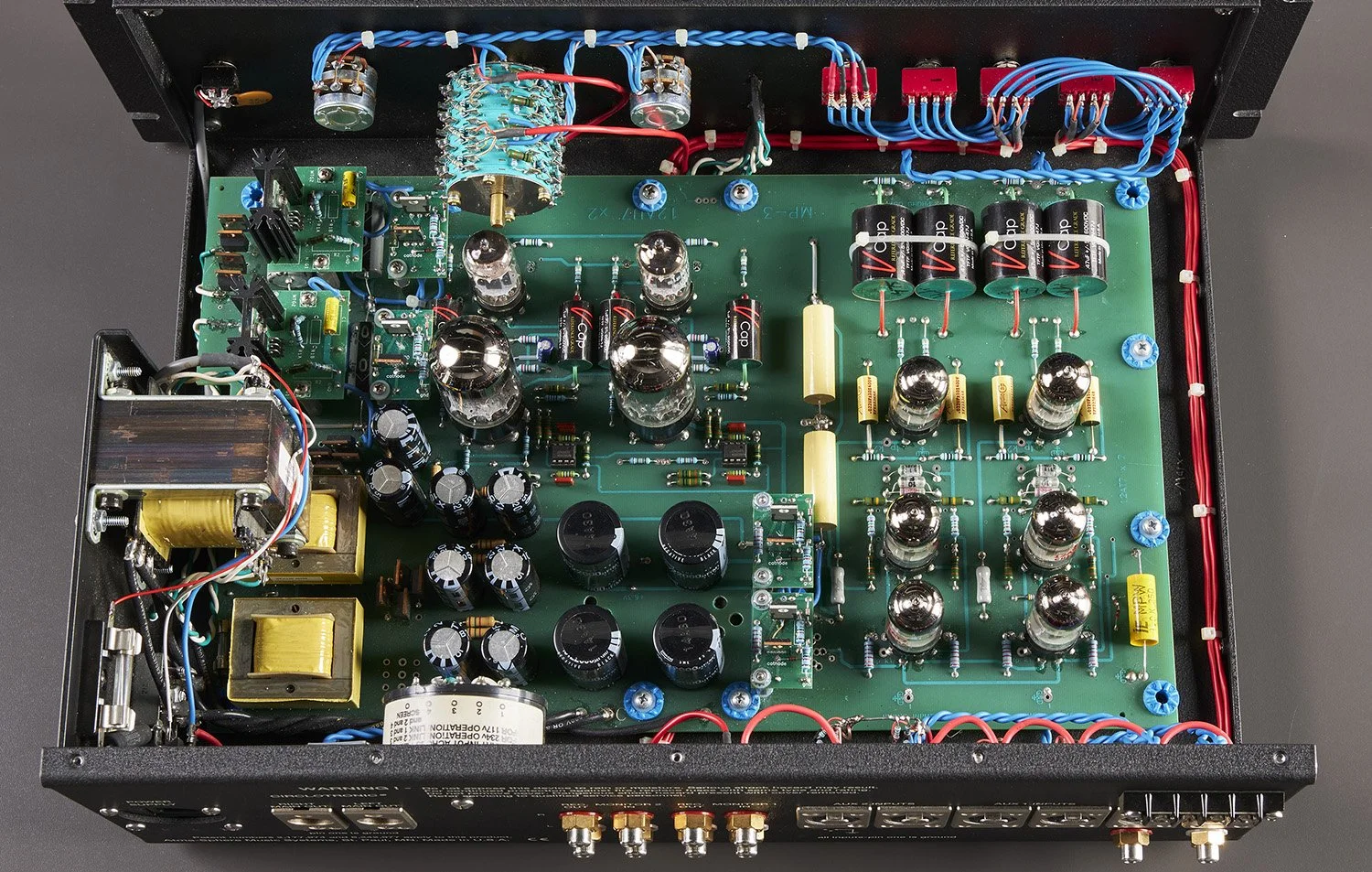 Innenansicht eines elektronischen Verstärkers mit mehreren Röhren, Kondensatoren und Leiterplatten, sichtbare Kabel und Stecker.