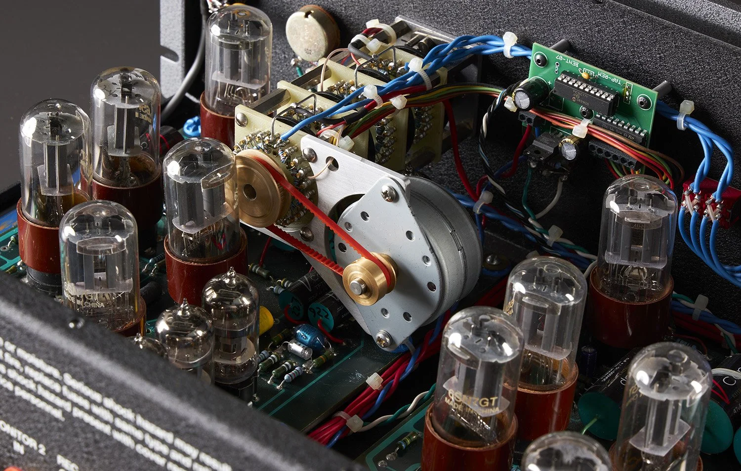 Innenansicht eines Röhrenverstärkers mit sichtbaren Vakuumröhren, Gummiriemen, Leiterplatten und Kabel.