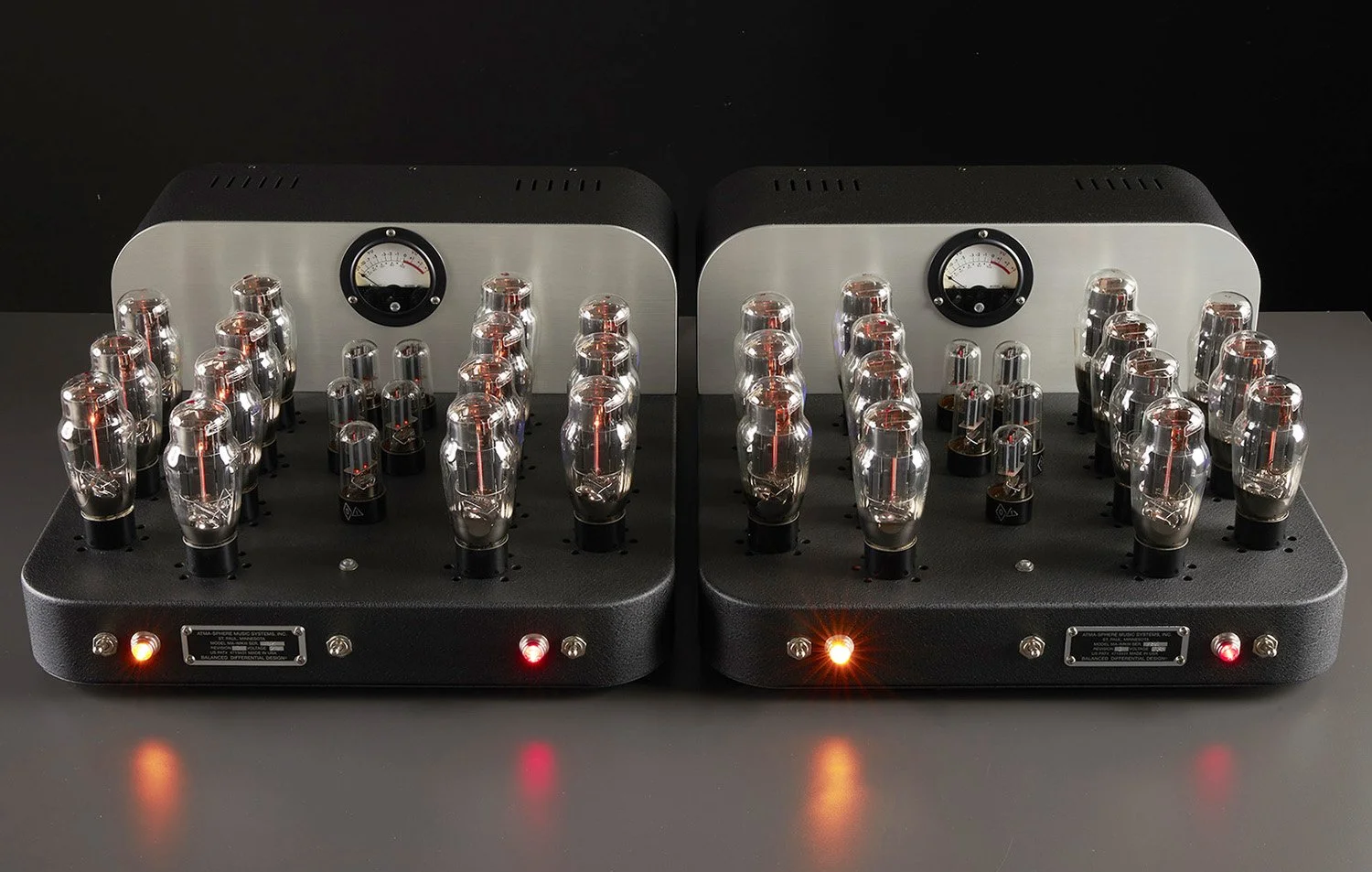 Zwei Röhrenverstärker mit Leuchtanzeigen und Vakuumröhren auf einer schwarzen Oberfläche.