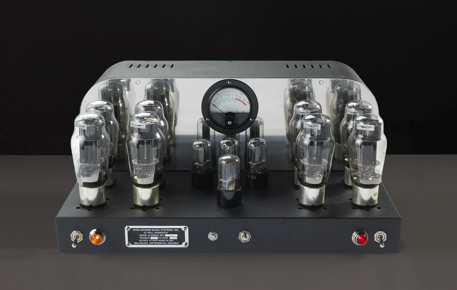 Ein elektronischer Musikverstärker mit Vakuumröhren auf einem schwarzen Tisch, mit einem schwarzen Hintergrund.