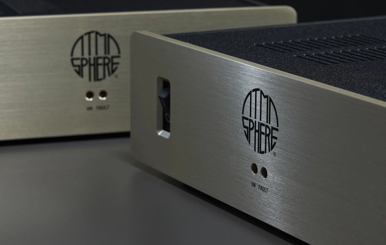 Nahaufnahme zweier ATOM Sphere Verstärker mit Metallgehäuse, logos und Kontrollleuchten auf der Vorderseite.