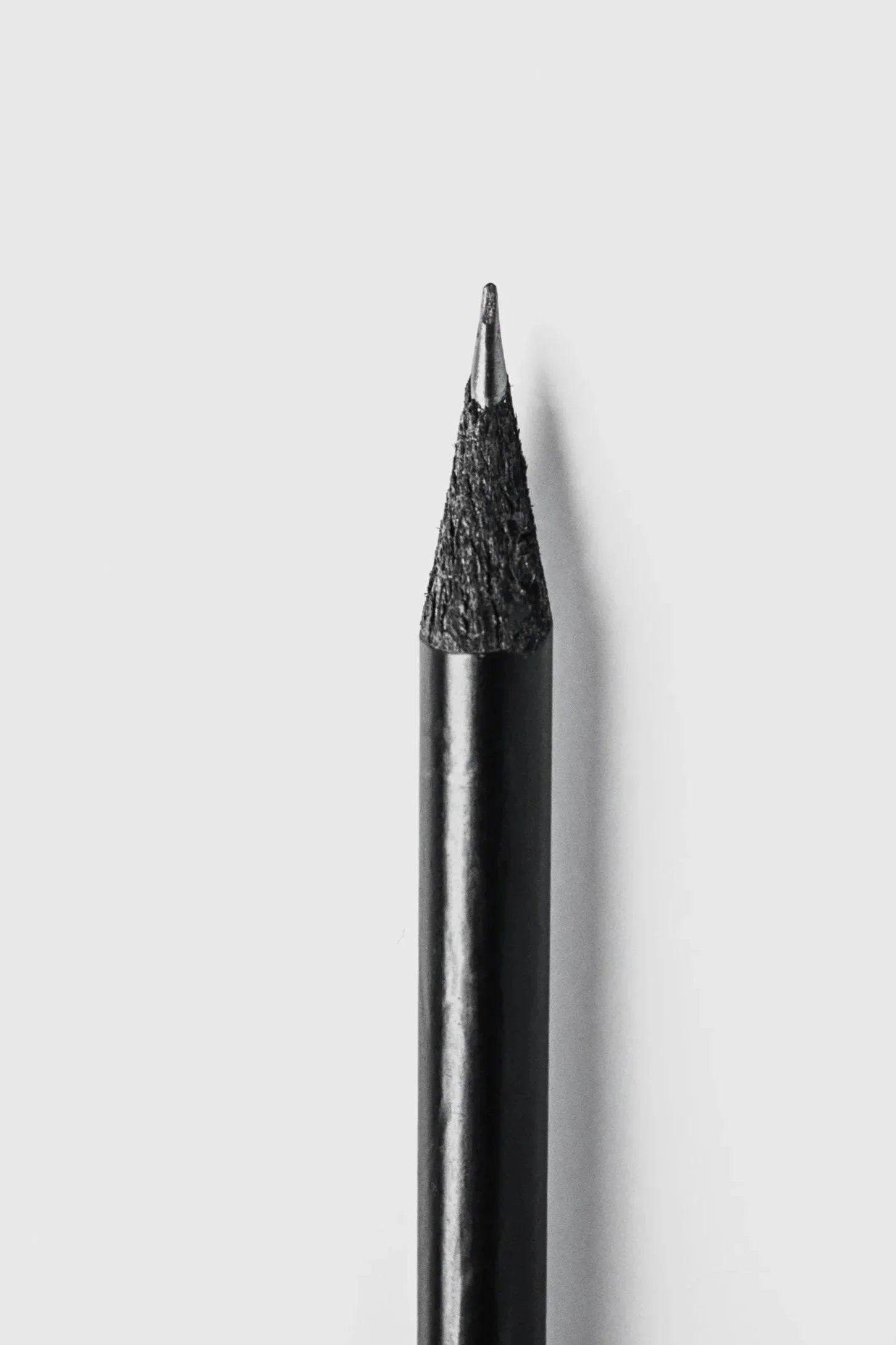 Close-up of a black pen with a sharpened tip, set against a white background.