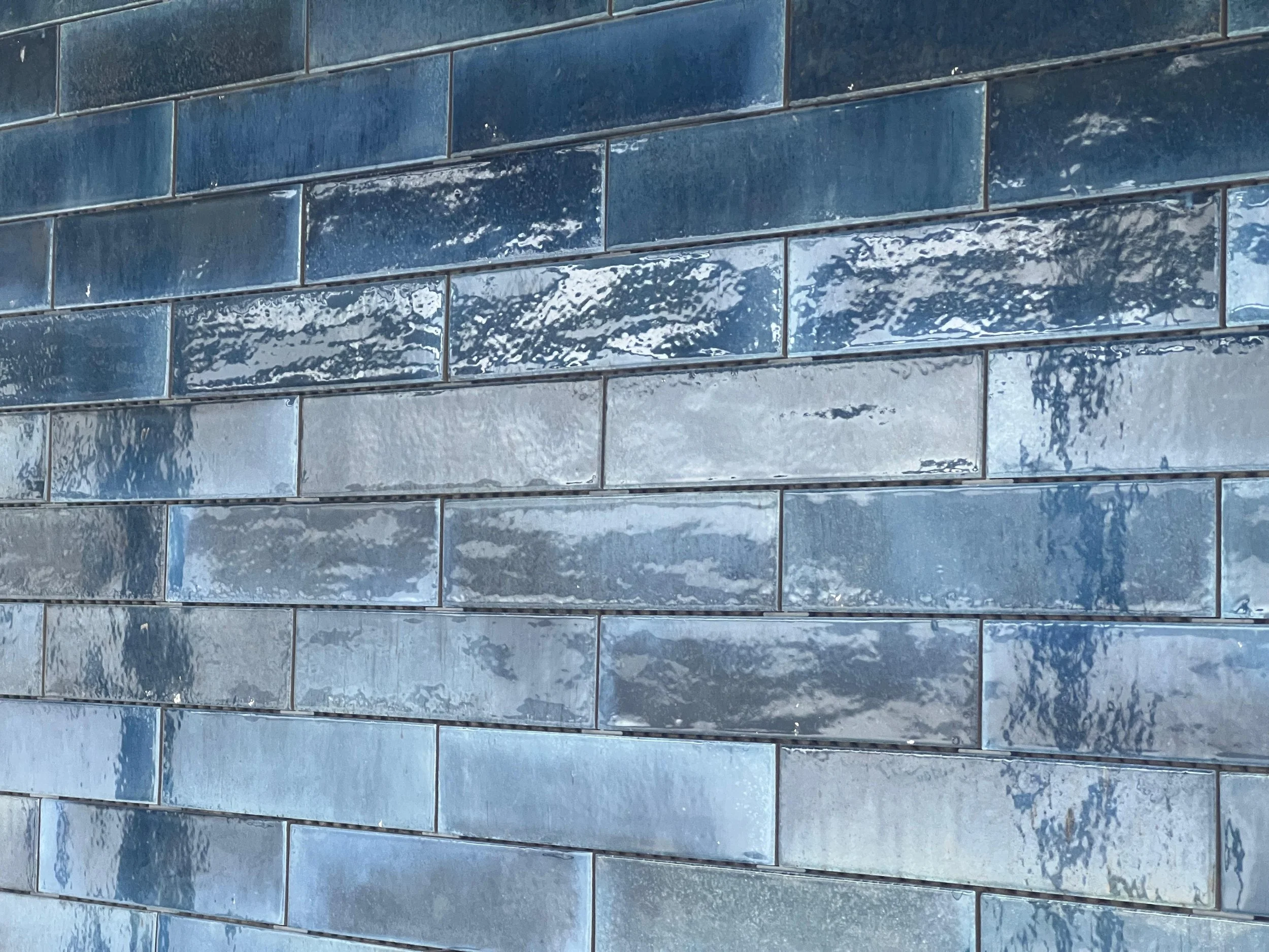 Close-up of blue ceramic subway tiles with a glossy finish.