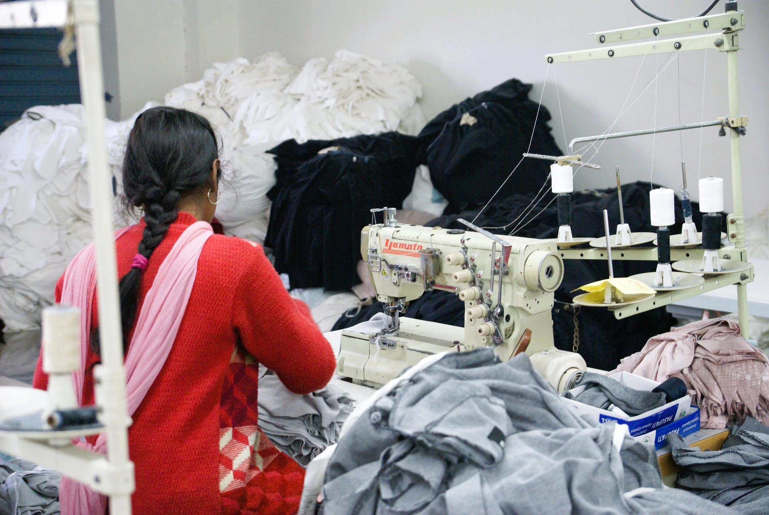 A garment worker stitches clothes in a factory, where seasonal demand fuels long hours in a city that produces much of India’s winter wardrobe. (Ludhiana, Punjab)
