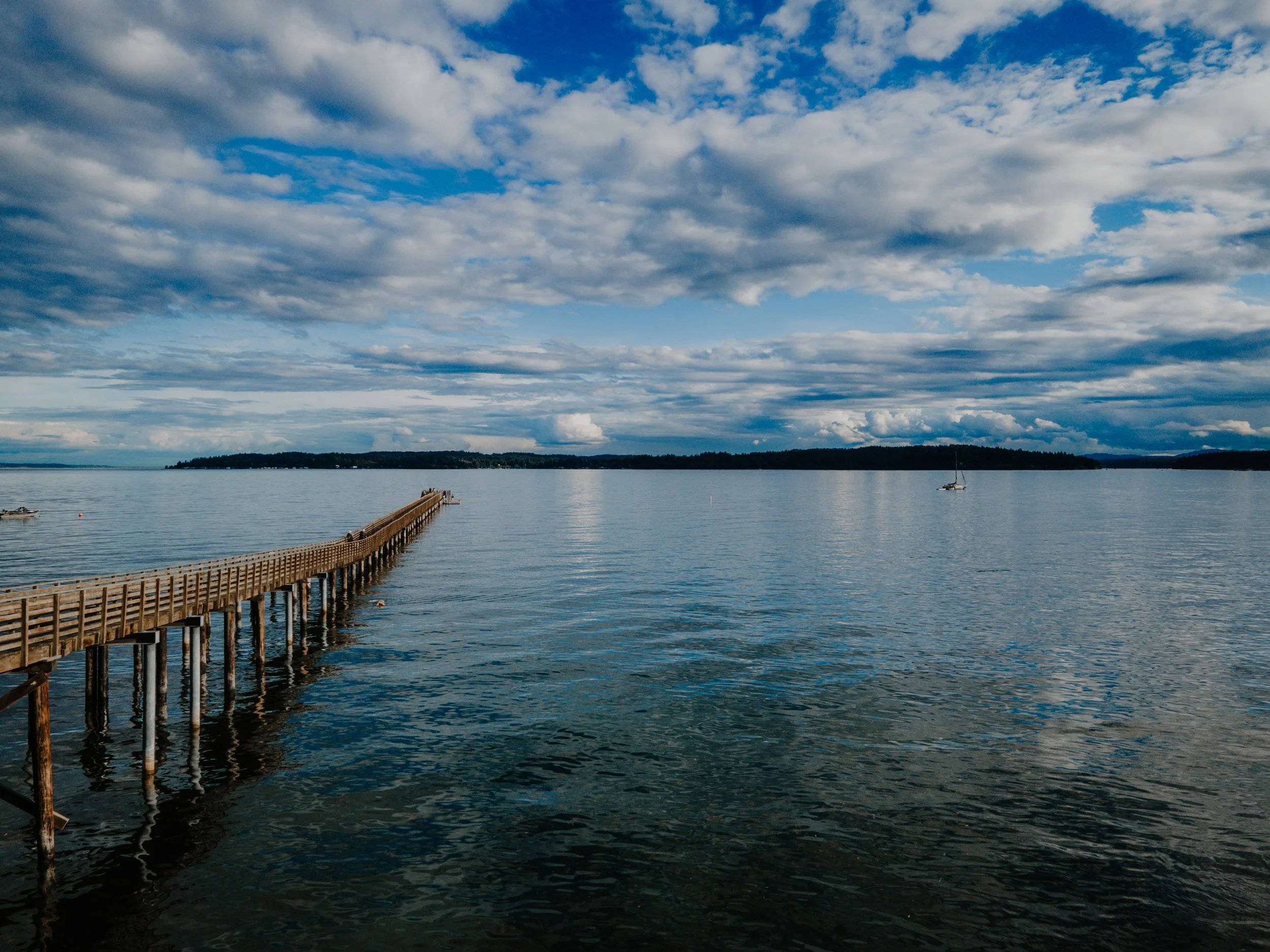 View of Indianola Pier with dappled clouds and calm waters
