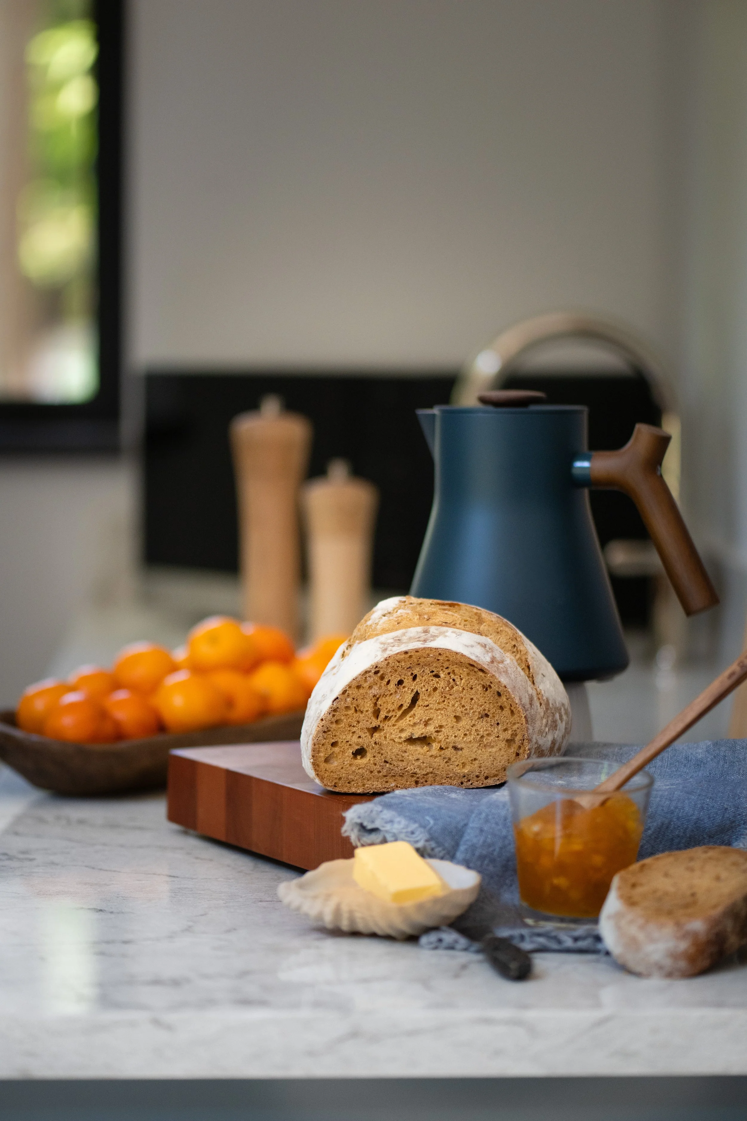 Fresh baked bread and butter in the kitchen with tangerines and blue electric kettle