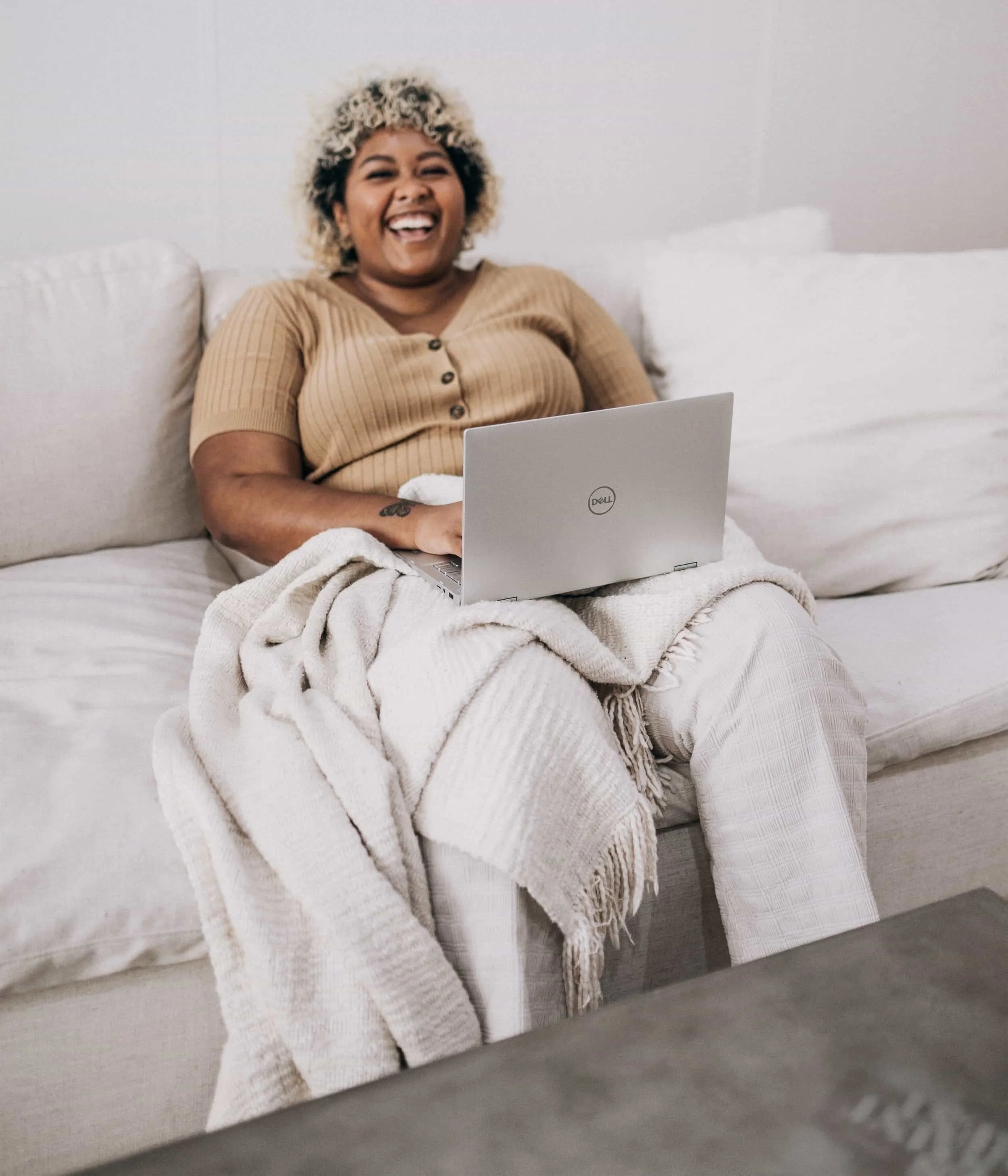 Woman sitting on couch smiling, with computer in her lap