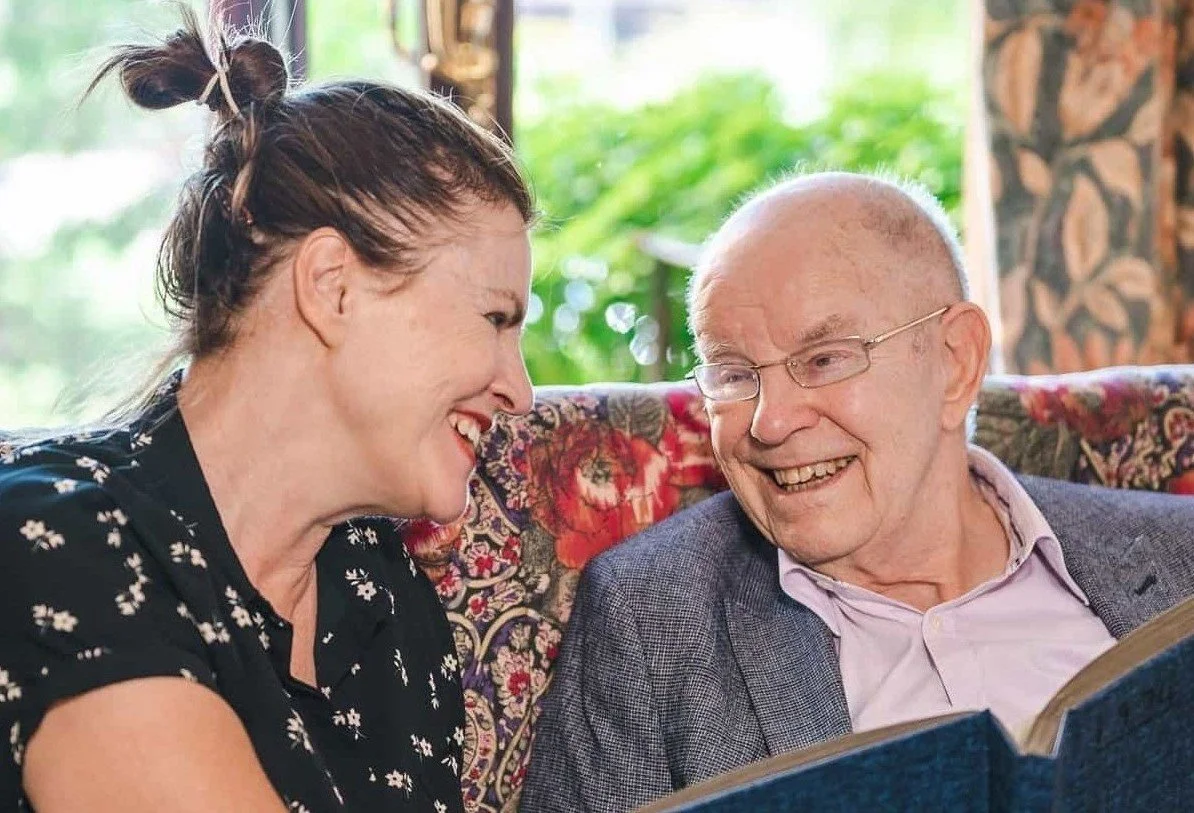 Woman and elderly man sitting smiling together 
