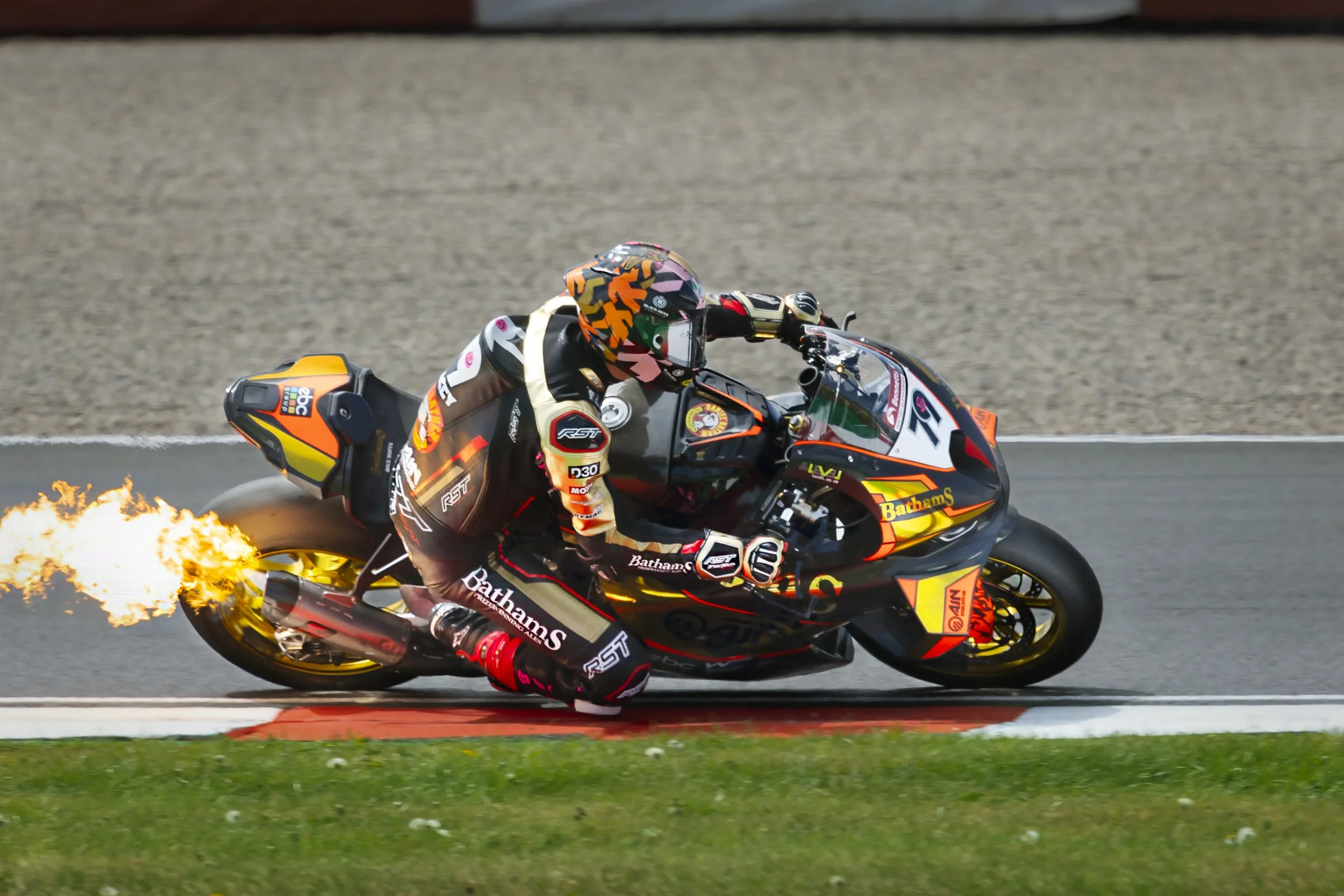 moto gp motorsport photograph taken at Donnington race track in the UK with fire coming out of back of motorcycle 