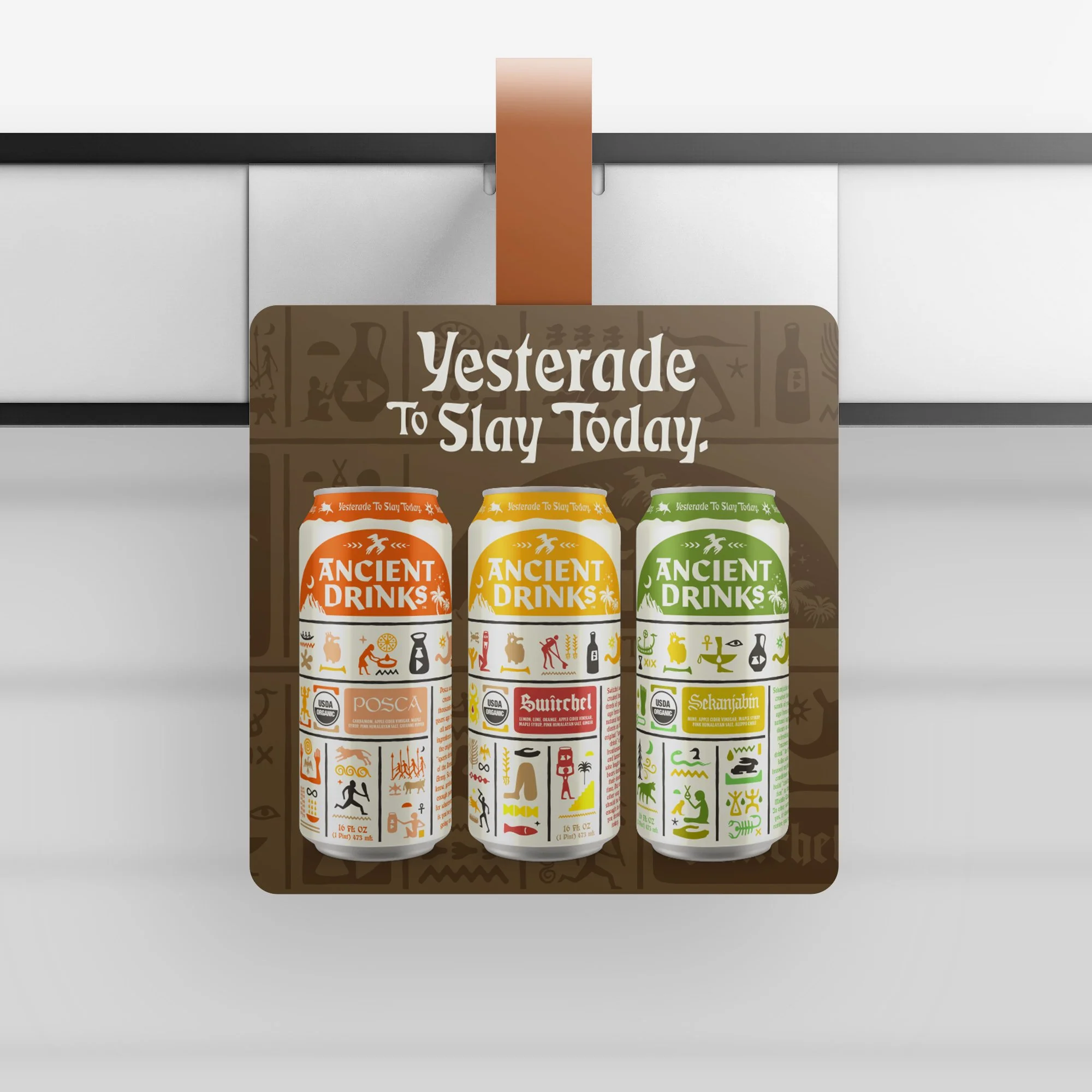 Three cans of ancient drinks with colorful labels in orange, yellow, and green, displayed in front of a sign that reads 'Yesteryear To Slay Today'. The sign features illustrations of ancient symbols and tools.