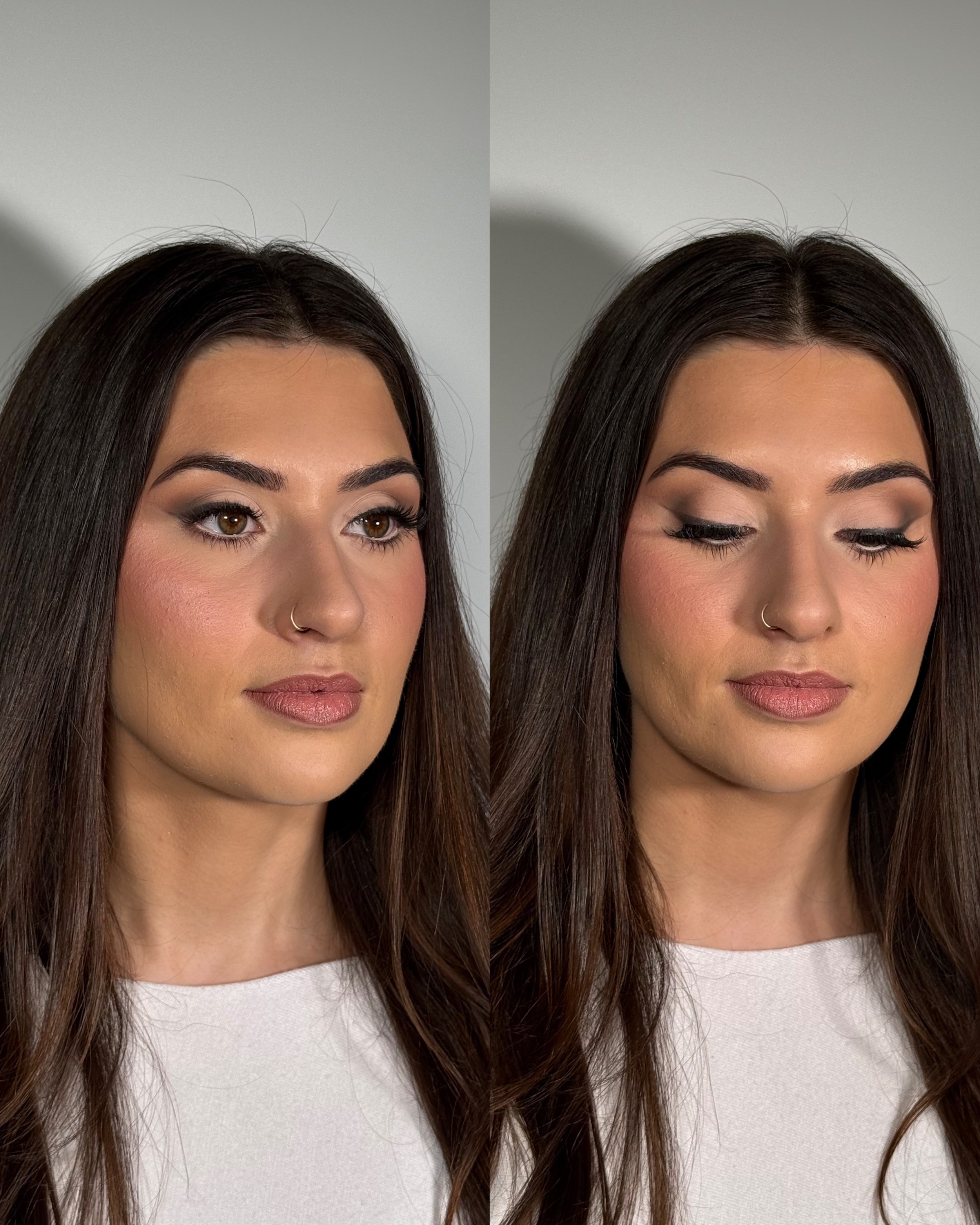 Close-up of a woman with long dark hair, wearing a white top, showing her face from the nose up, with makeup including defined eyebrows, eyeliner, and lipstick.