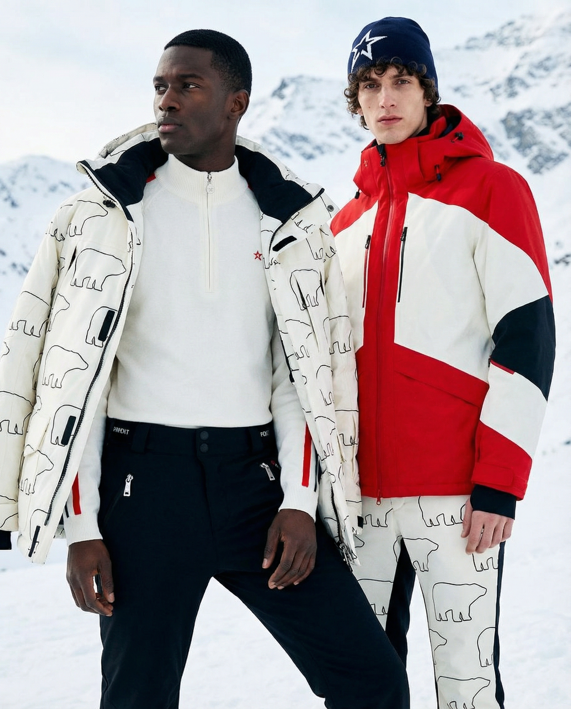Two men standing close together in a snowy mountain landscape wearing winter jackets. The man on the left is Black with short hair, wearing a white jacket with an elephant print and black pants. The man on the right is Caucasian with curly hair, wear