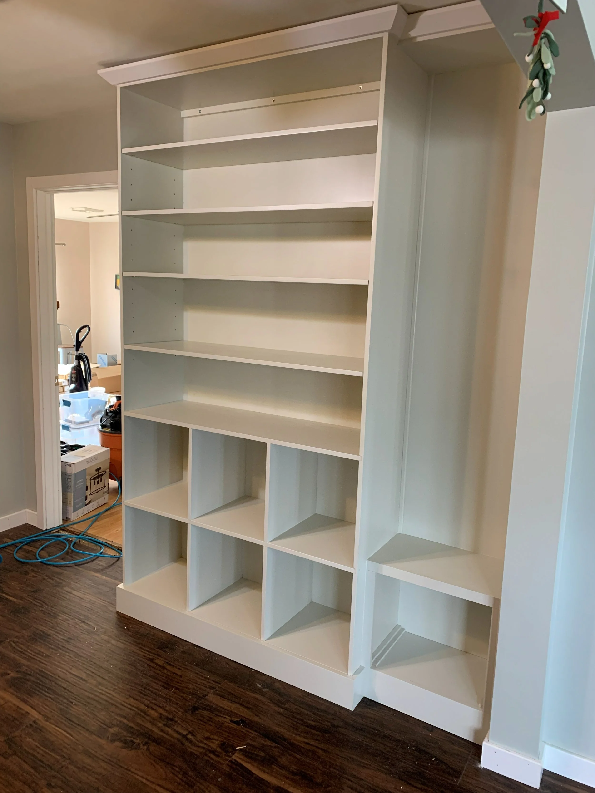 R.E. Arnold's Custom Construction. Empty white bookshelves with multiple shelves and cubbies.