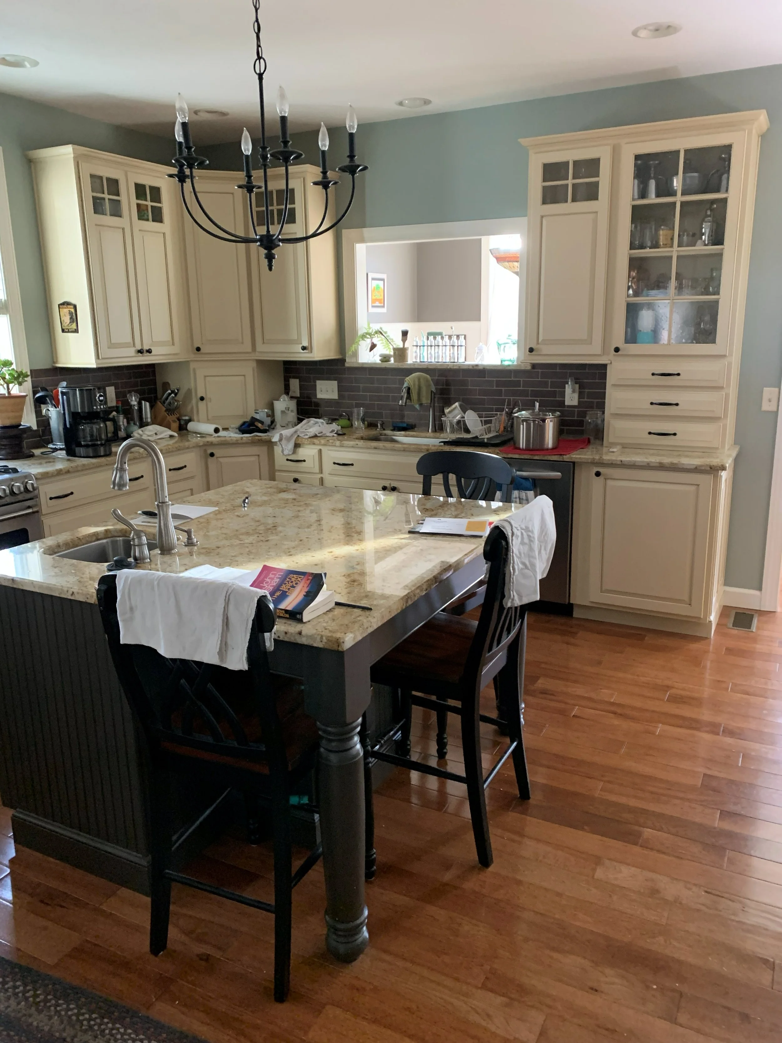 R.E. Arnold's Custom Construction. A kitchen install with cream-colored cabinets, a granite island, and a chandelier. 