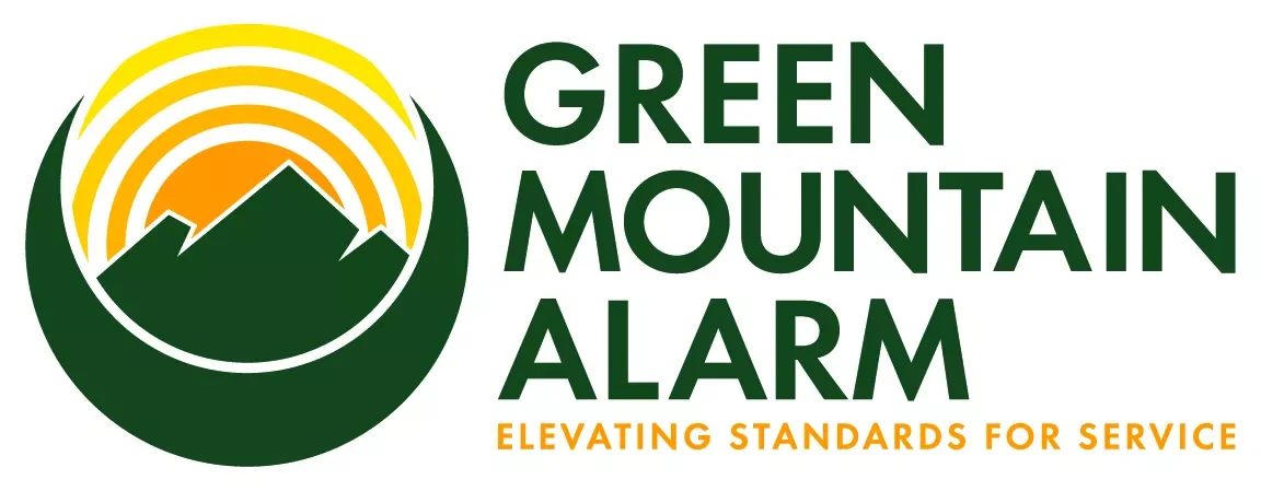 Logo for Green Mountain Alarm featuring a mountain silhouette with orange rays of the sun rising behind it, accompanied by the text "GREEN MOUNTAIN ALARM" in green and "ELEVATING STANDARDS FOR SERVICE" in orange.