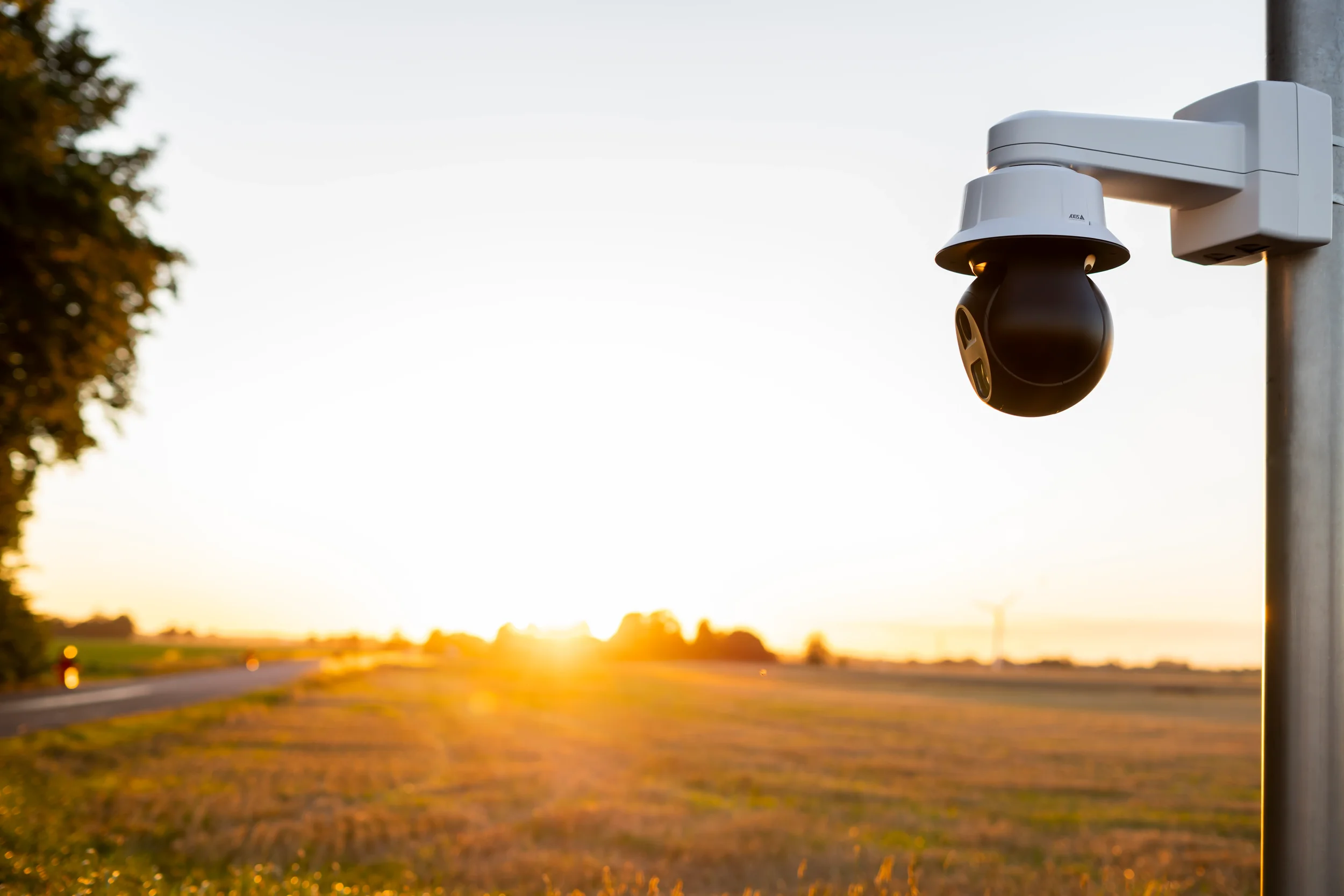 Outdoor CCTV security camera monitoring an open field during sunset