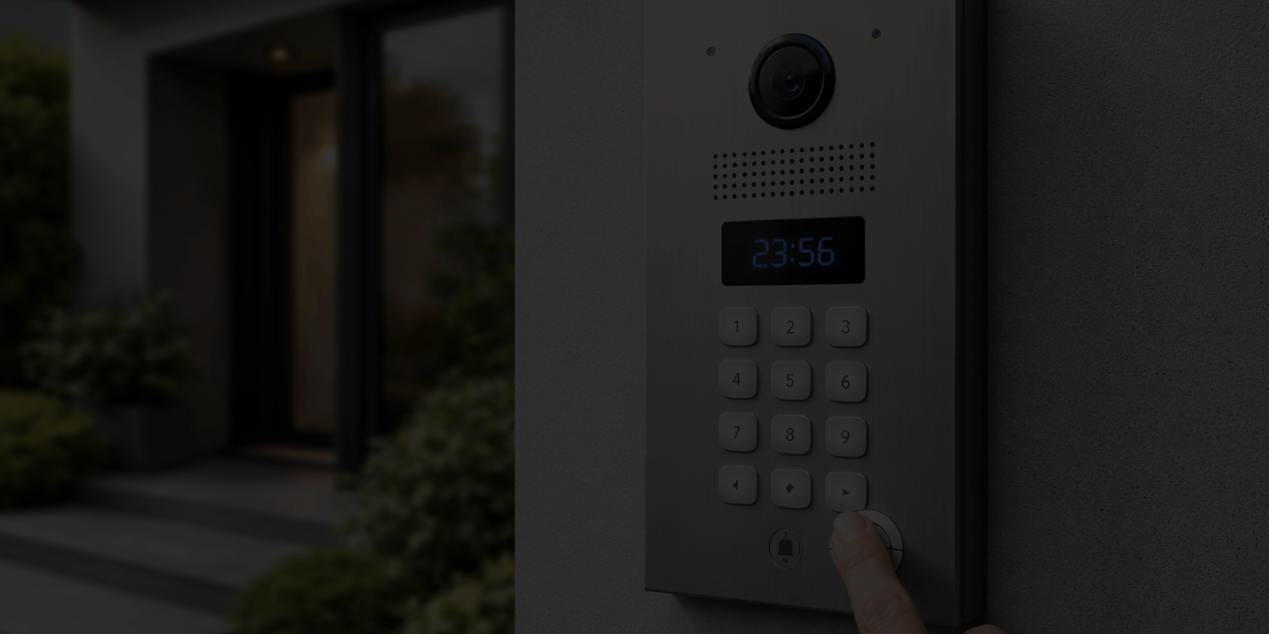 Close-up of a person pressing a button on a modern doorbell intercom system outside a house, with the house's entrance and greenery blurred in the background.