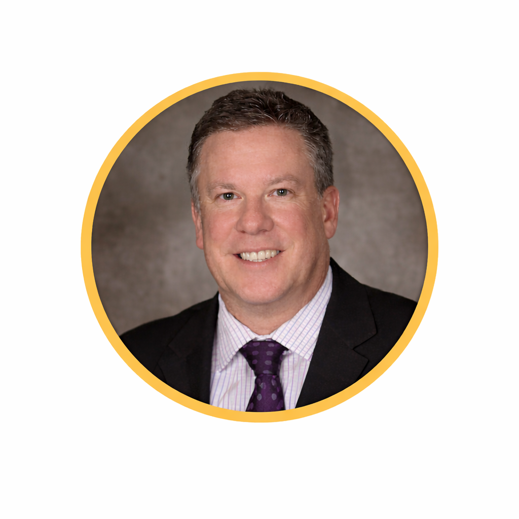 Professional headshot of a man in a suit and tie, smiling, with a gray background and a yellow circular border.