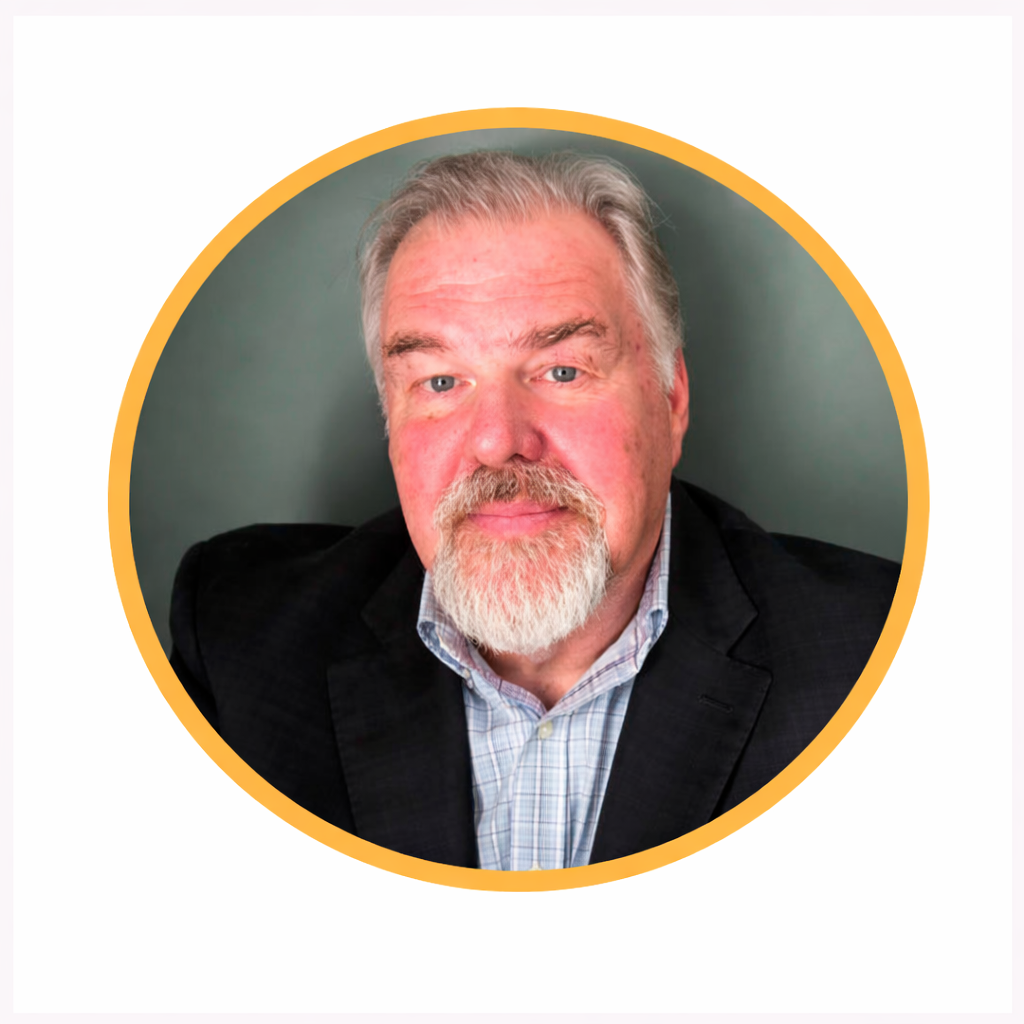 Portrait of a middle-aged man with gray hair and beard, wearing a black blazer and a checkered shirt, against a green background, framed by a yellow circle.