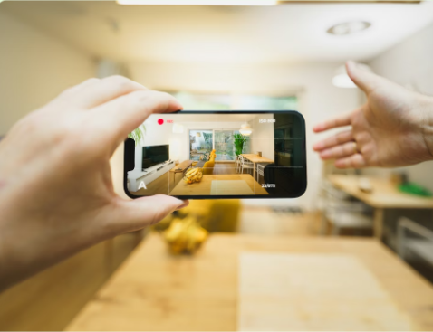 Person taking a photo of a living room using a smartphone with a hand reaching out.