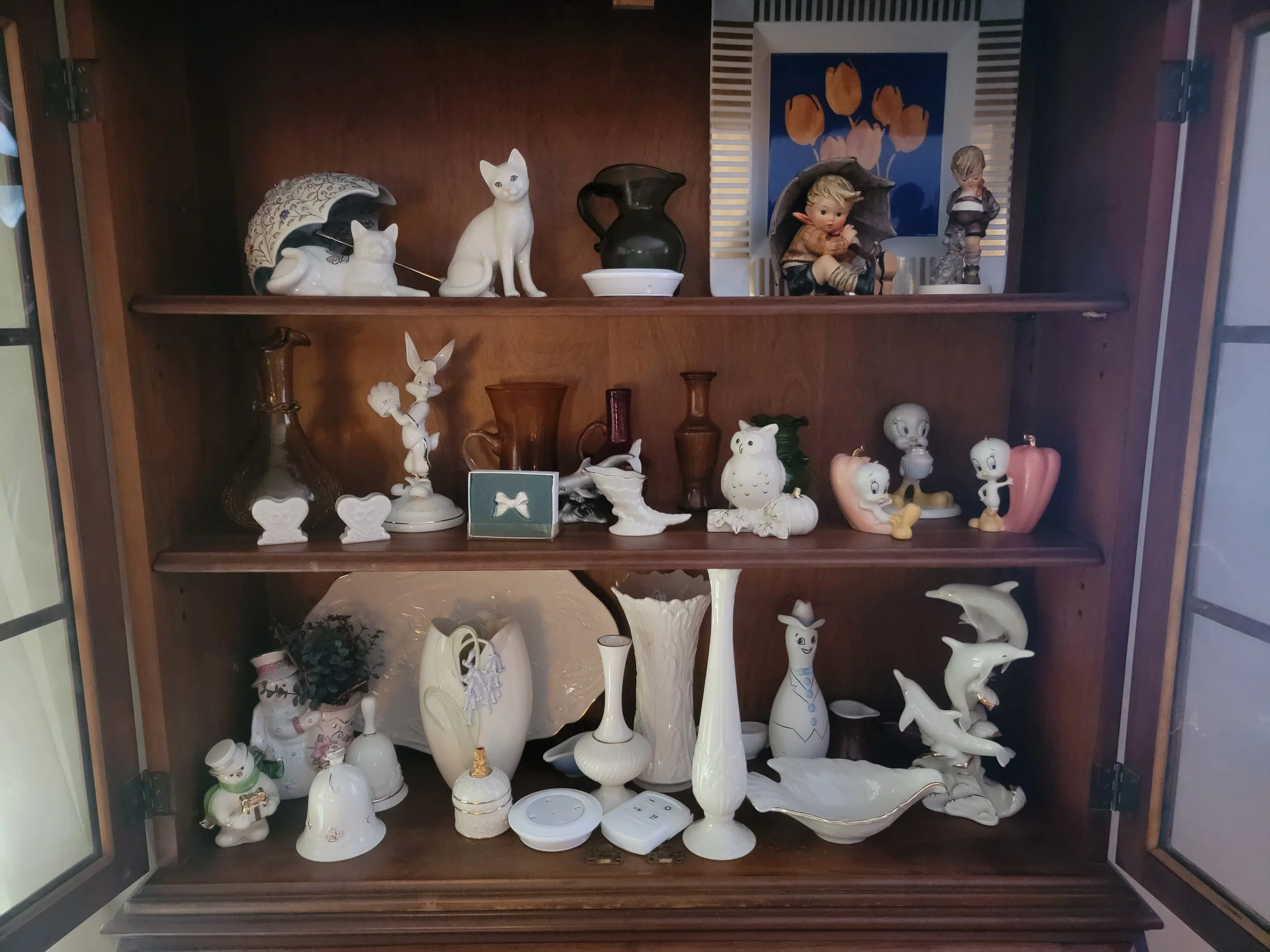 Display cabinet with organized collectible items prepared for estate sale inventory and pricing.