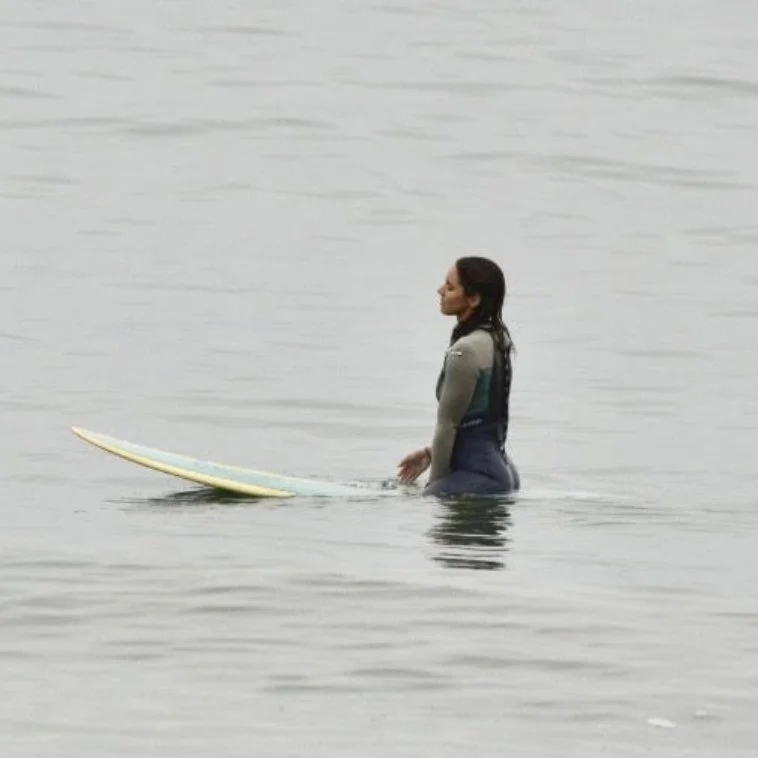 Photo of Michelle Cortrite sitting on a surf board in the ocean