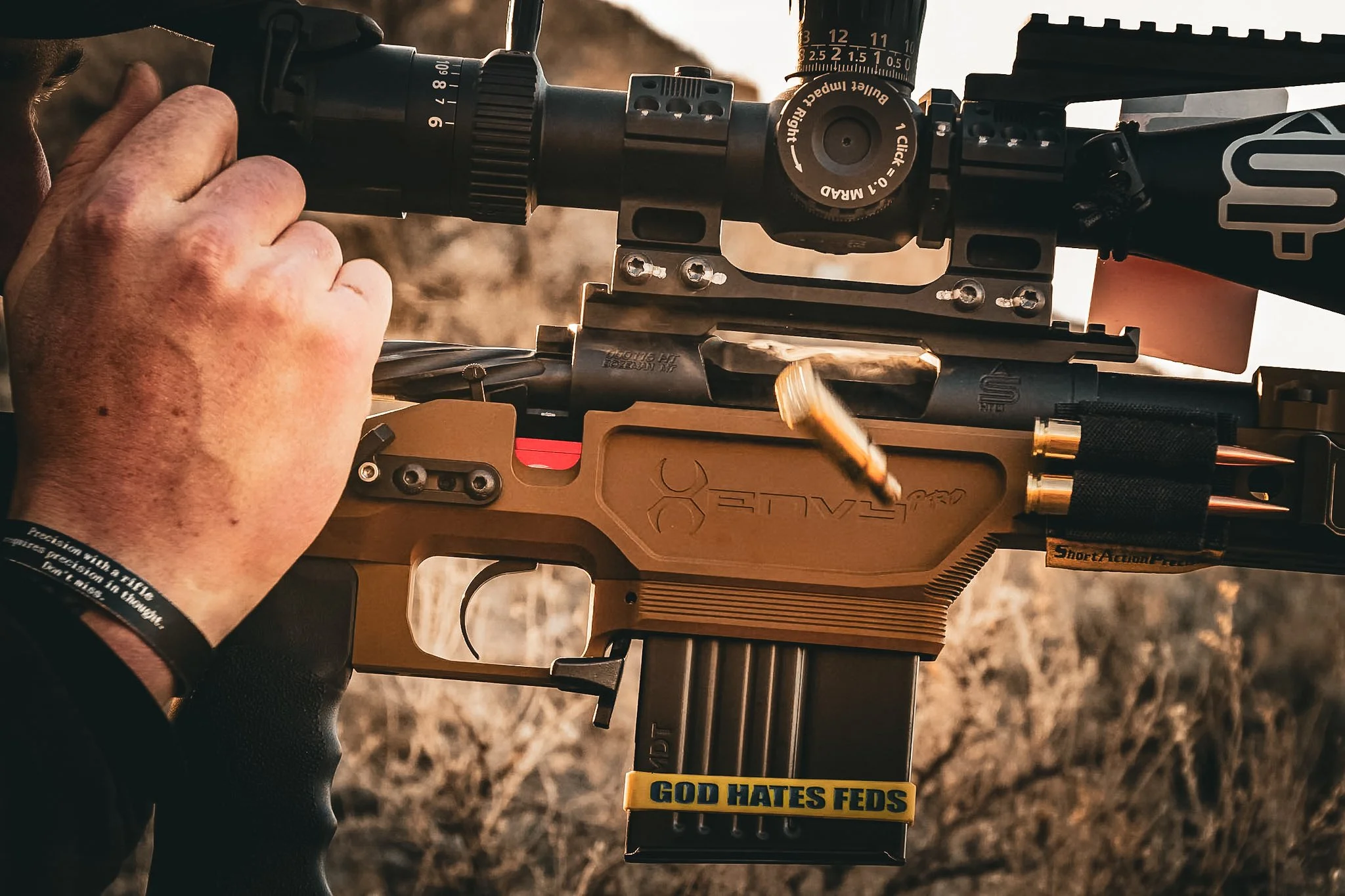 Close-up of a person holding a rifle with a scope mounted on it, outdoors during daytime.