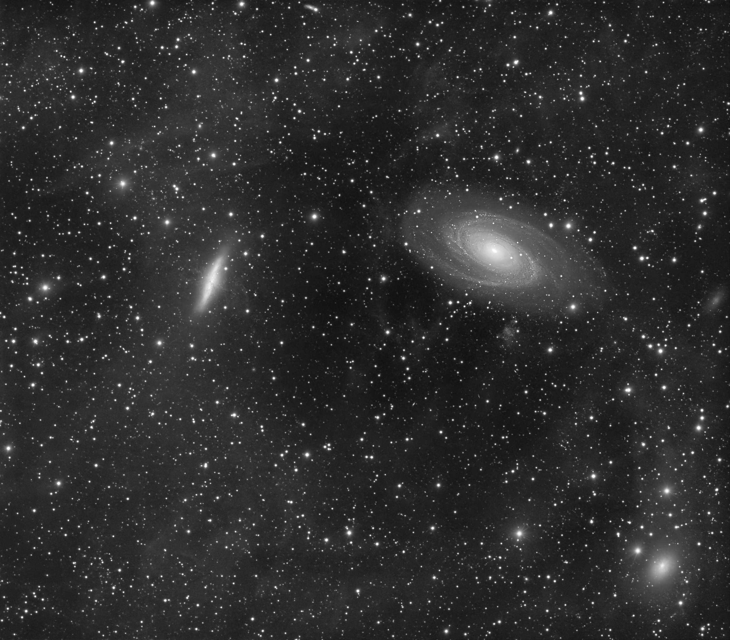 A black-and-white photograph of countless stars and distant galaxies in space, with a bright two galaxies M81 and M82