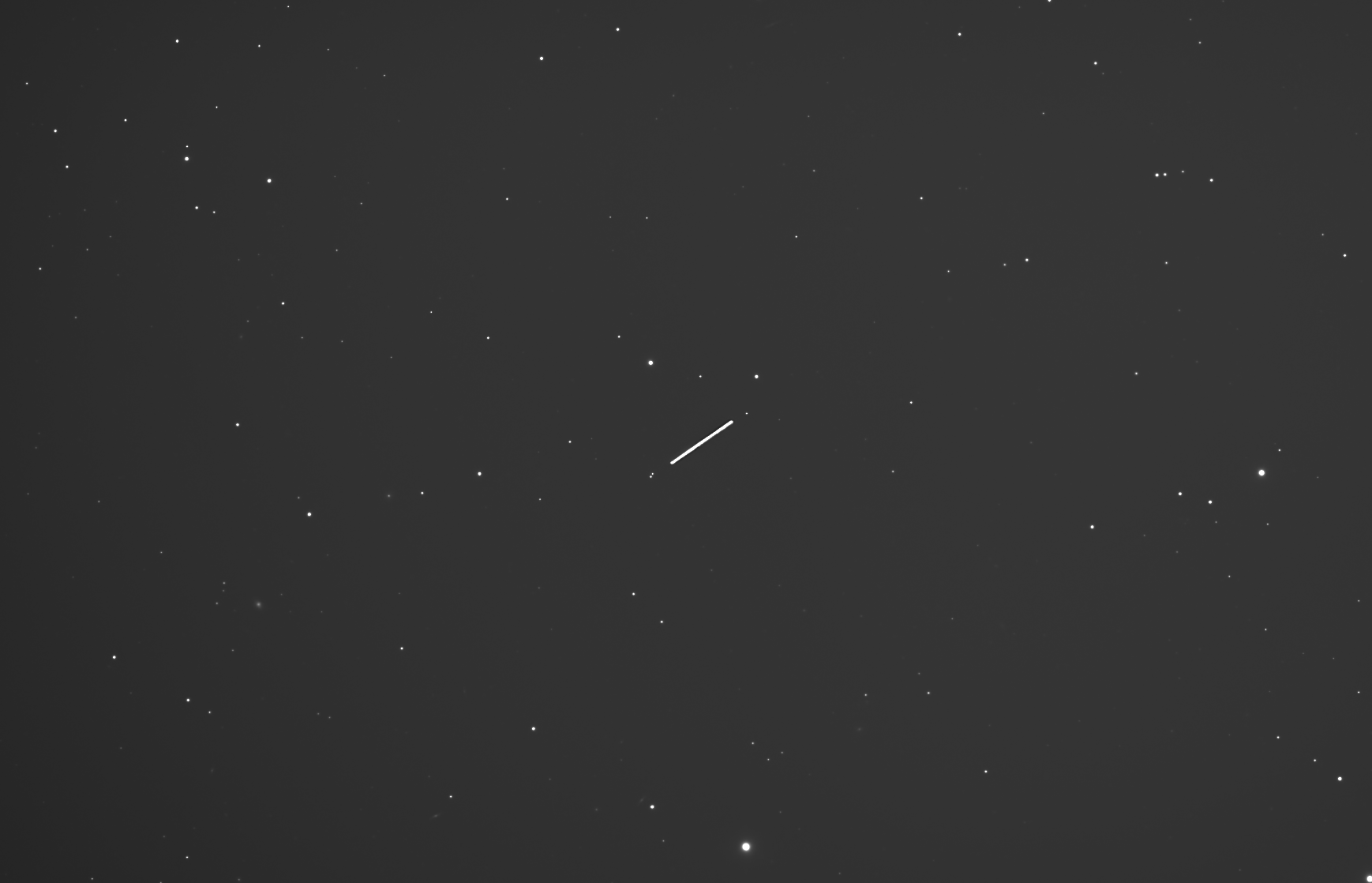 Black and white photo of a star field sky with a streak of light, which is Asteroid Massalia passing through the sky over the period of 2.5 hours
