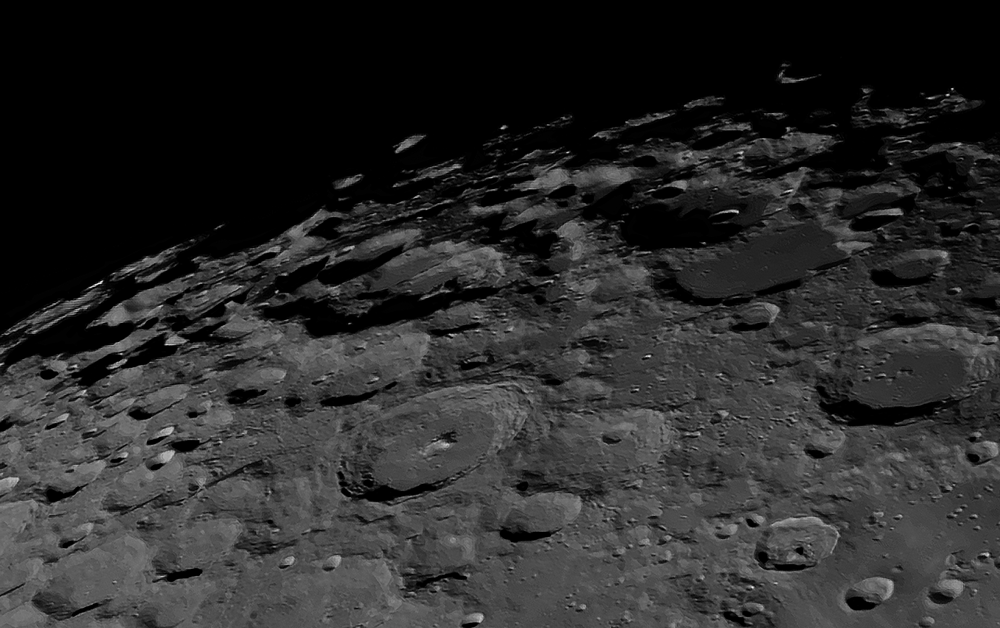 Close-up view of the moon's  south pole heavily cratered surface with the blackness of space in the background.