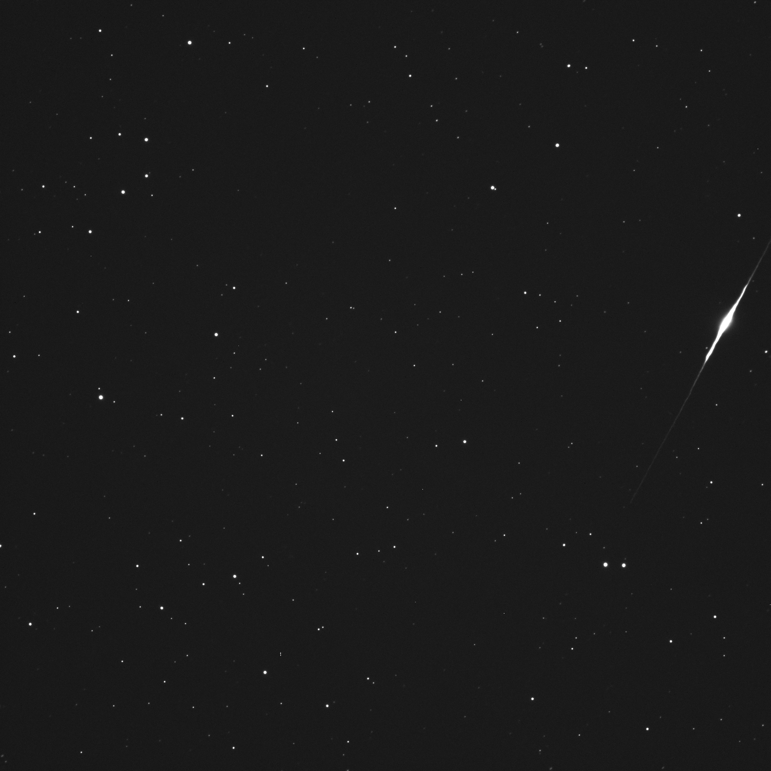 Night sky filled with numerous stars and a bright streak of a meteor or shooting star on the right side.