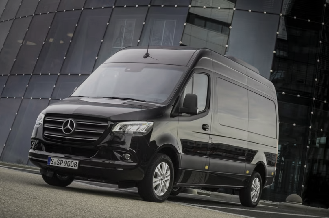 Black Mercedes-Benz commercial van parked in front of a modern glass building.