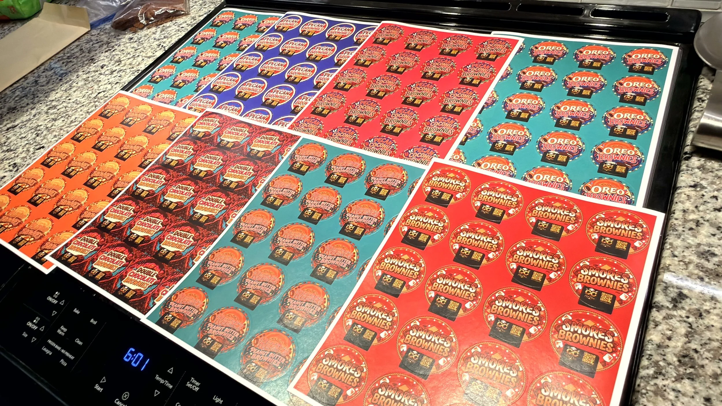 Sheet of printable stickers for Oreo cookies, pecan crescent brownies, double chocolate brownies, and s'mores brownies, laid out on a kitchen counter.