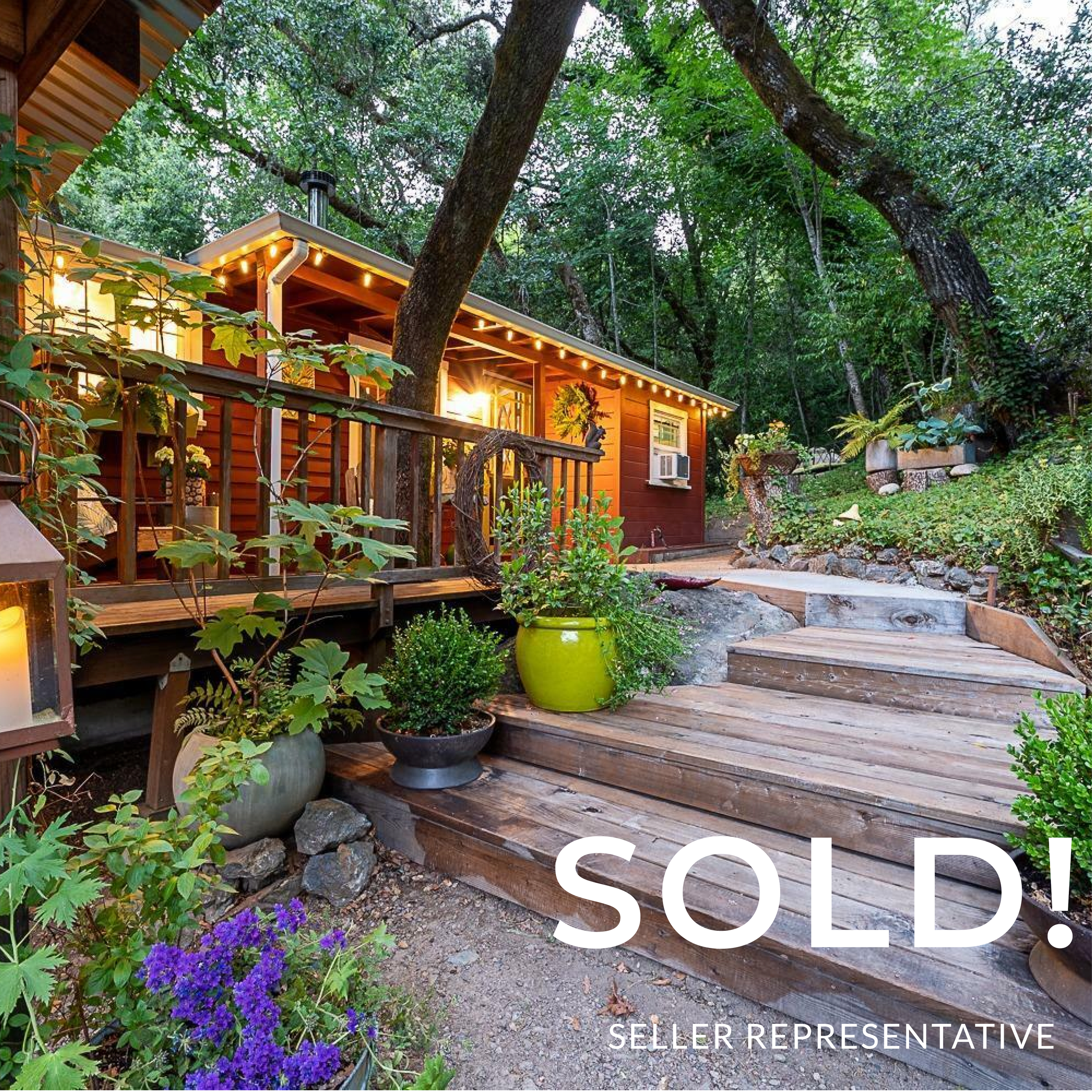 A cozy wooden house with a deck surrounded by lush greenery and potted plants, illuminated by warm outdoor lights. The image has a large white text overlay that says "SOLD!" and smaller text reading "SELLER REPRESENTATIVE."