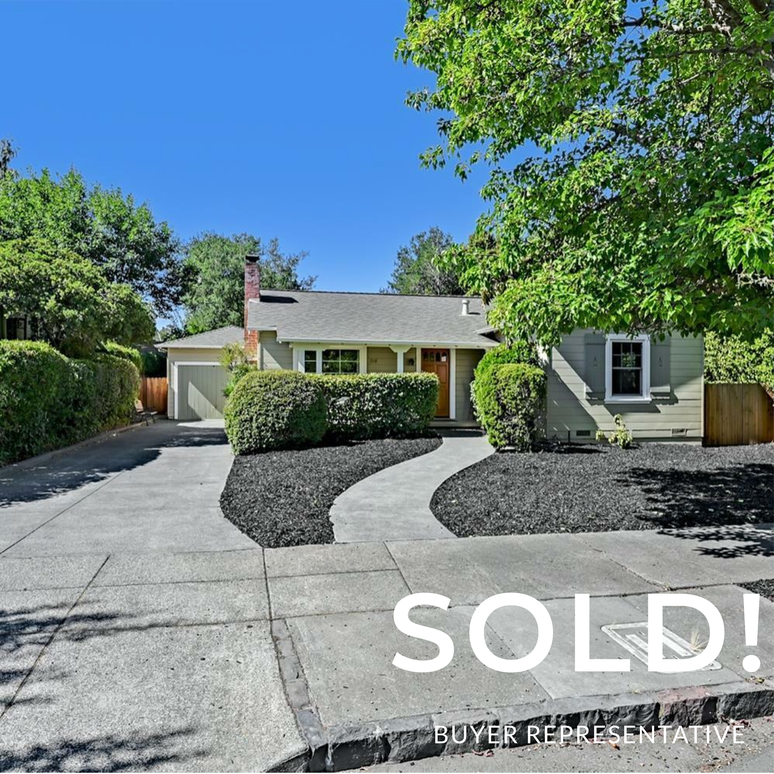 Front view of a sold house with a concrete driveway and well-manicured bushes.