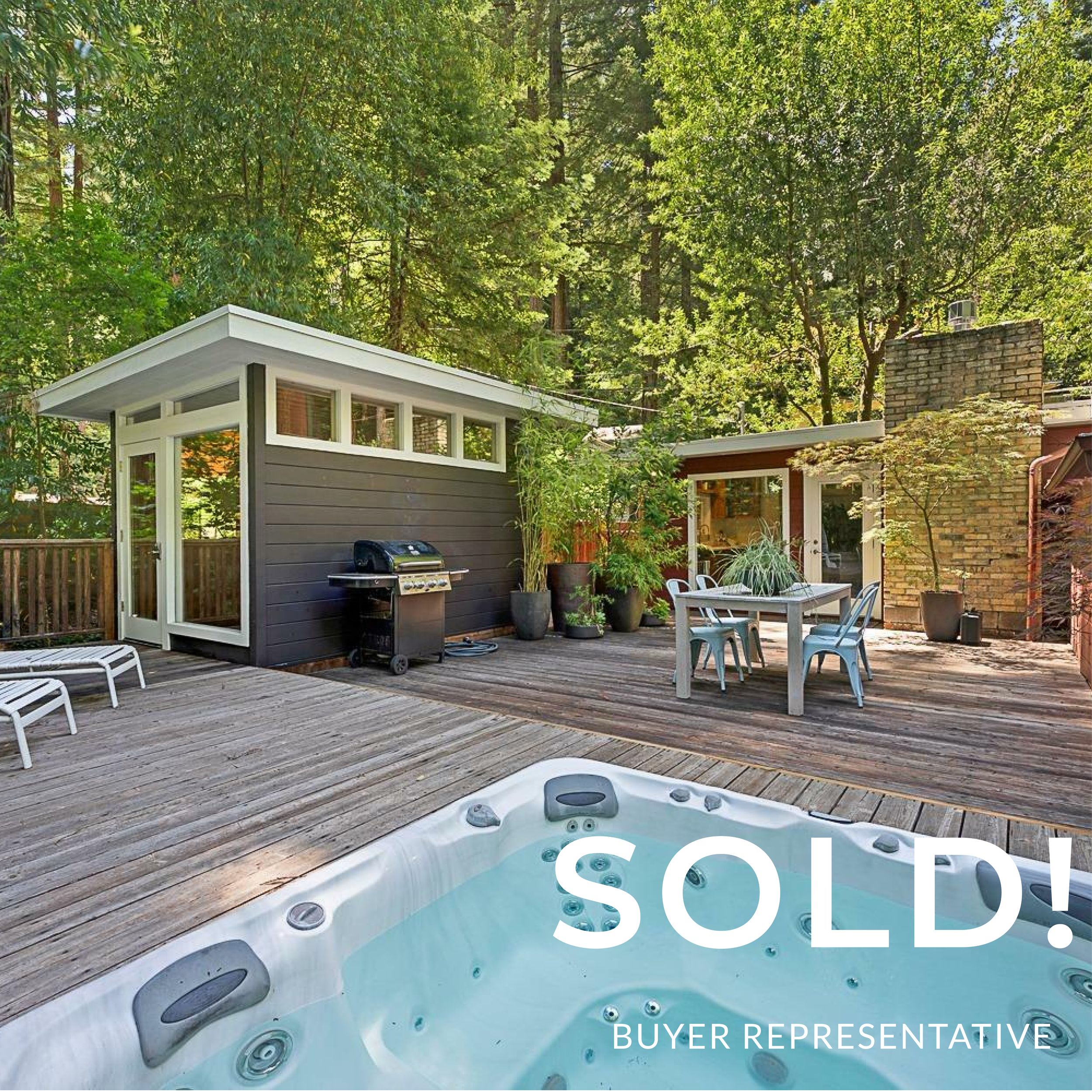 Outdoor deck with hot tub, patio table with chairs, lounge chairs, potted plants, small building, and forest background.