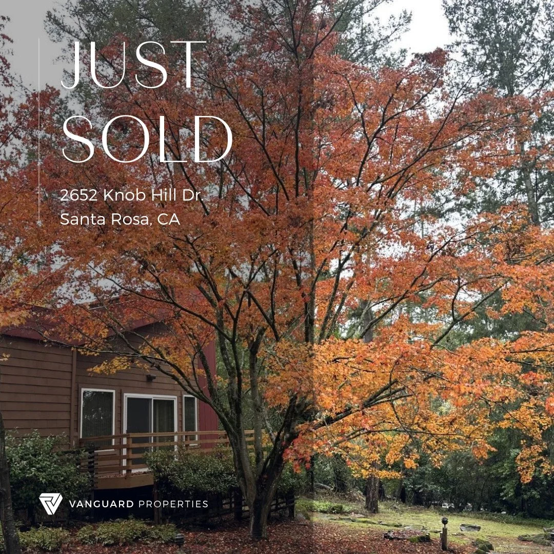 A house with a brown exterior and white-framed windows is surrounded by trees with orange and red autumn leaves. The image has a 'Just Sold' overlay with the address 2652 Knob Hill Dr, Santa Rosa, CA, and a Vanguard Properties logo.
