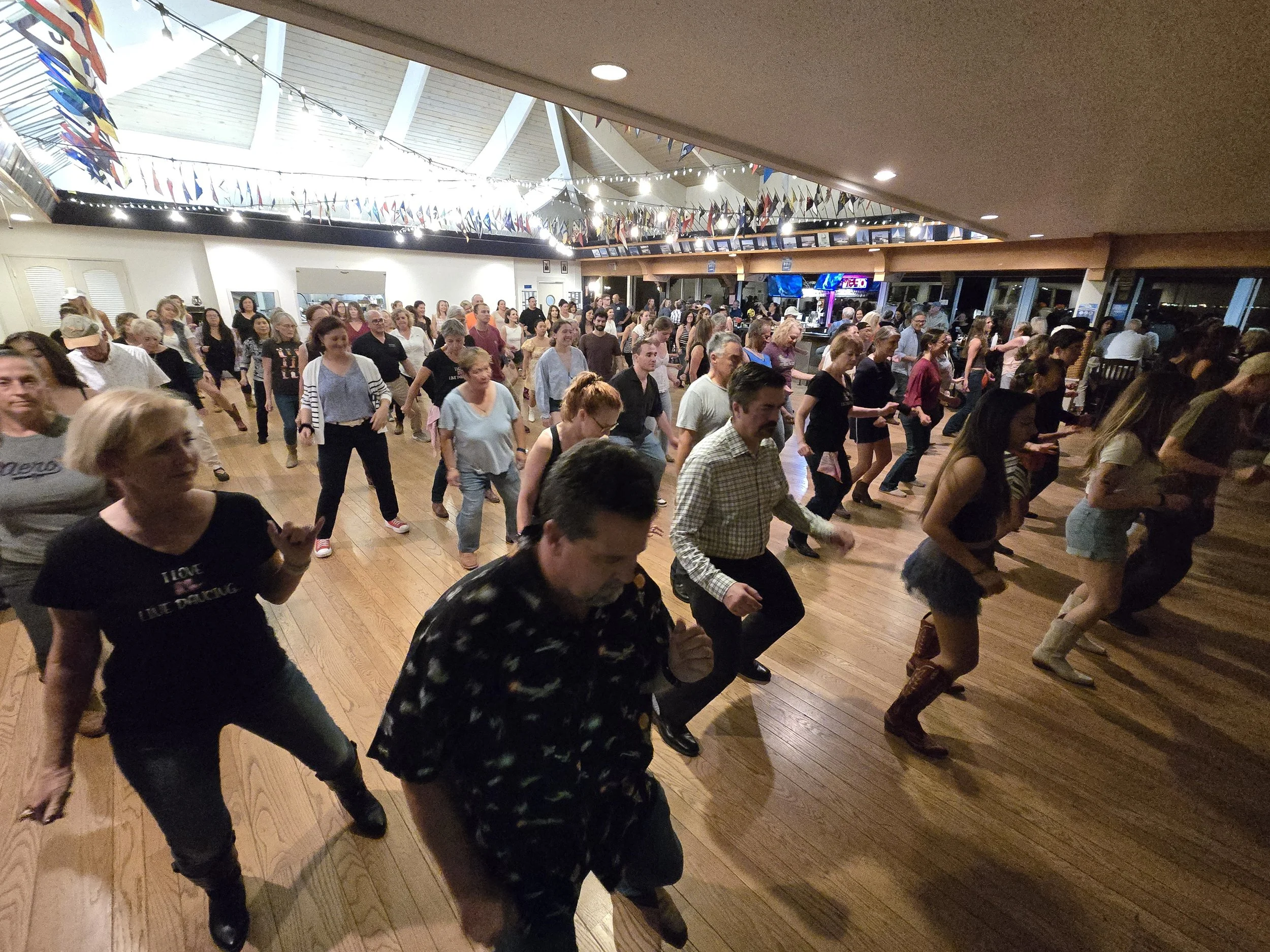 Large crowd line dancing at DJ Shivers country dance night at Coyote Point Yacht Club in San Mateo with live instruction and high-energy music.