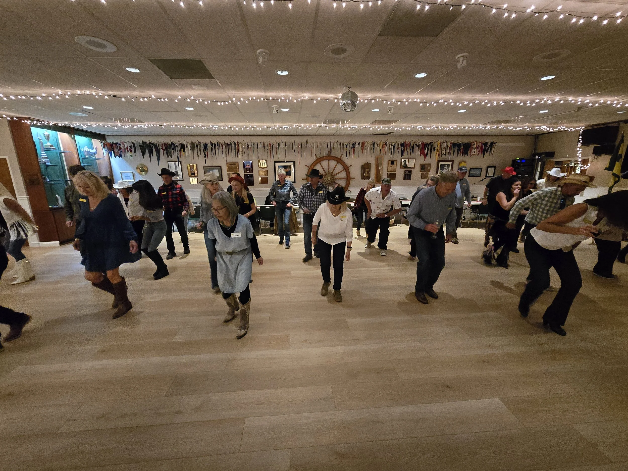 Group of people dancing in a rustic, decorated room with string lights, nautical flags, and country-themed decor at a DJ Shivers event in San Mateo.