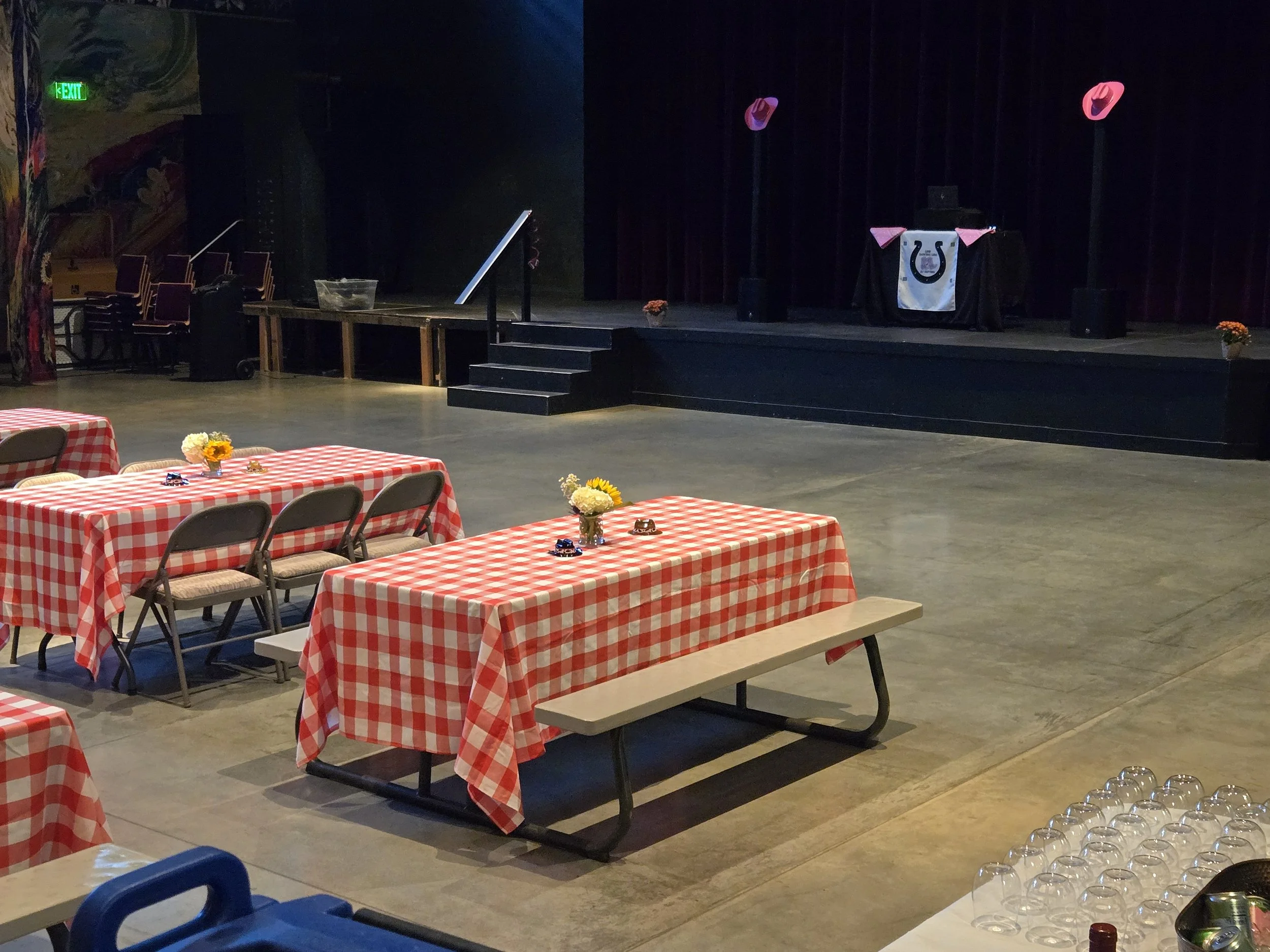 picnic style tables in front of a dance floor and on the stage is the speakers and dj booth set up for dj shivers at a private event