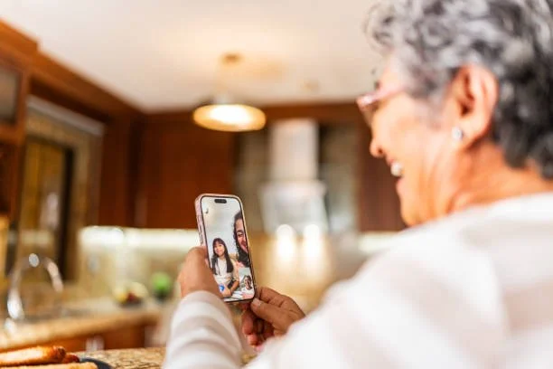 An elderly woman taking a selfie with a young girl and smiling in a kitchen.