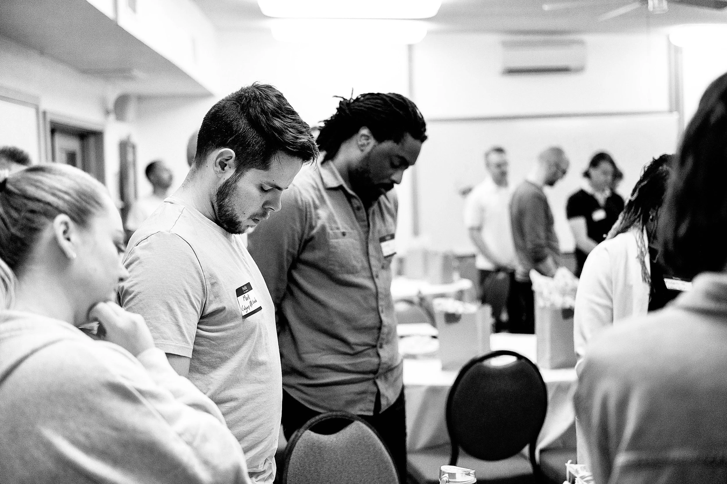 People praying with heads bowed in a church or prayer room.