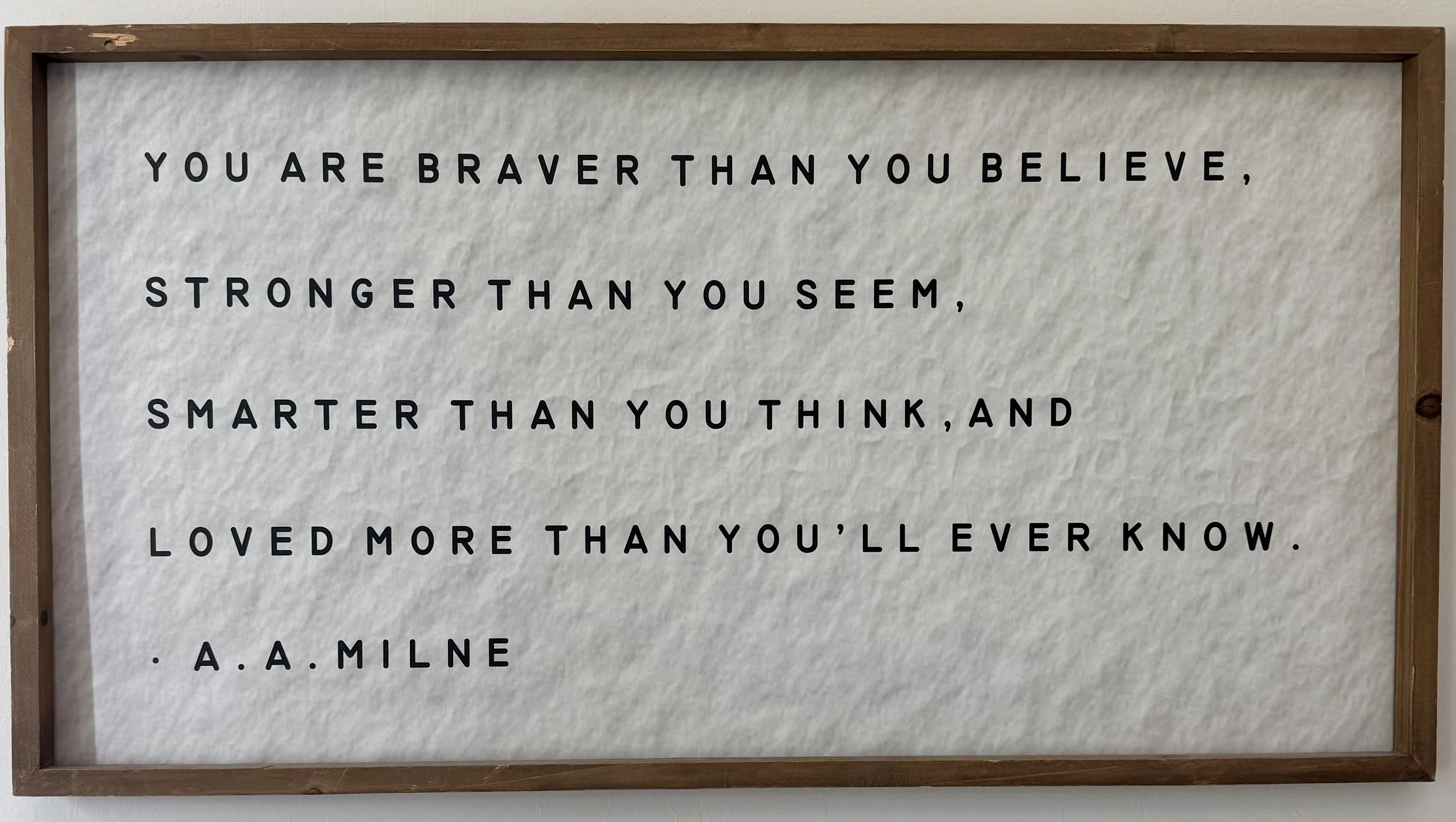 framed quote on a wall that reads: "You are braver than you believe, stronger than you seem, smarter than you think, and loved more than you'll ever know. - A. A. Milne"