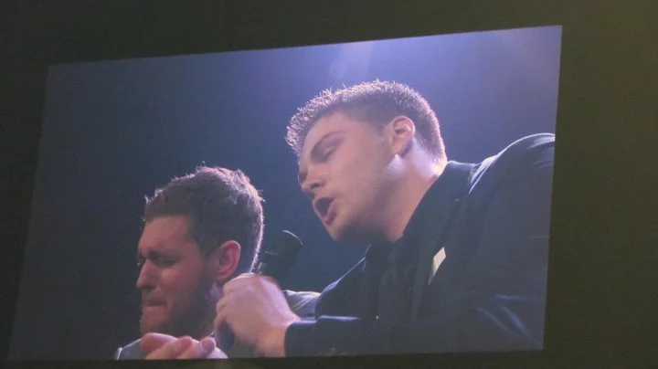 Two men are performing on stage, holding microphones and singing passionately.