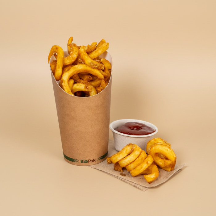 French fries and onion rings with a side of ketchup in a small paper cup on a napkin against a beige background.
